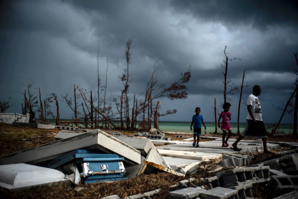 People walk next to a shattered and water-filled coffin lays exposed to the elements in the aftermath of Hurricane Dorian, at the cemetery in Mclean's Town, Grand Bahama, Bahamas, Friday Sept. 13, 2019. (AP Photo/Ramon Espinosa) People walk next to a shattered and water-filled coffin lays exposed to the elements in the aftermath of Hurricane Dorian, at the cemetery in Mclean's Town, Grand Bahama, Bahamas, Friday Sept. 13, 2019. (AP Photo/Ramon Espinosa)