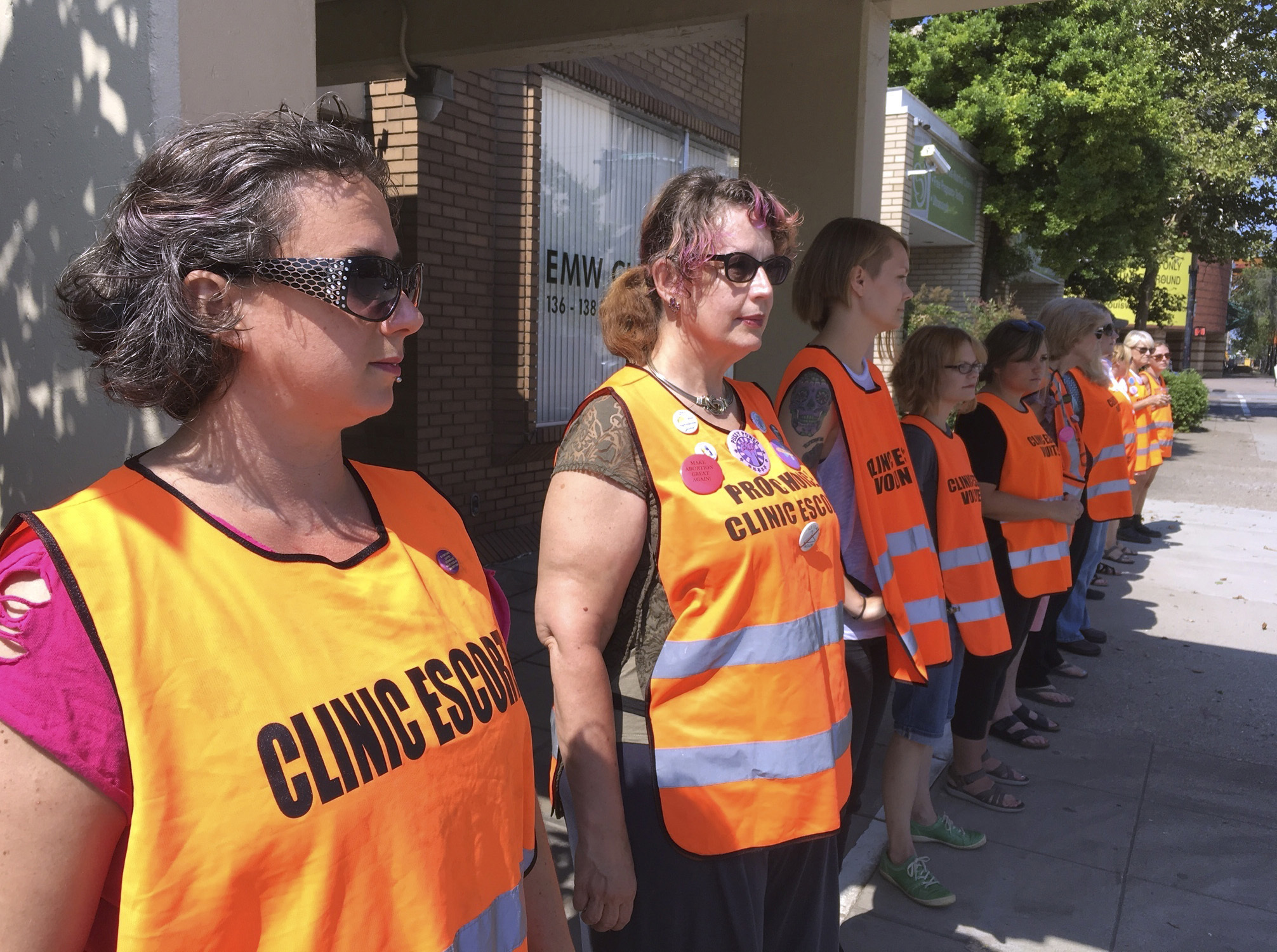 FILE - In this July 17, 2017 file photo, escort volunteers line up outside the EMW Women's Surgical Center in Louisville, Ky. Kentucky's Republican governor has signed a measure putting new restrictions on abortion, and his lawyers filed a response to a lawsuit already aimed at blocking it, Tuesday, March 19, 2019. Before Gov. Matt Bevin signed the measure, the American Civil Liberties Union challenged the legislation in a federal lawsuit. The new law bans abortion for women seeking to end their pregnancies because of the gender, race or disability of the fetus. (AP Photo/Dylan Lovan, File) FILE - In this July 17, 2017 file photo, escort volunteers line up outside the EMW Women's Surgical Center in Louisville, Ky. Kentucky's Republican governor has signed a measure putting new restrictions on abortion, and his lawyers filed a response to a lawsuit already aimed at blocking it, Tuesday, March 19, 2019. Before Gov. Matt Bevin signed the measure, the American Civil Liberties Union challenged the legislation in a federal lawsuit. The new law bans abortion for women seeking to end their pregnancies because of the gender, race or disability of the fetus. (AP Photo/Dylan Lovan, File)