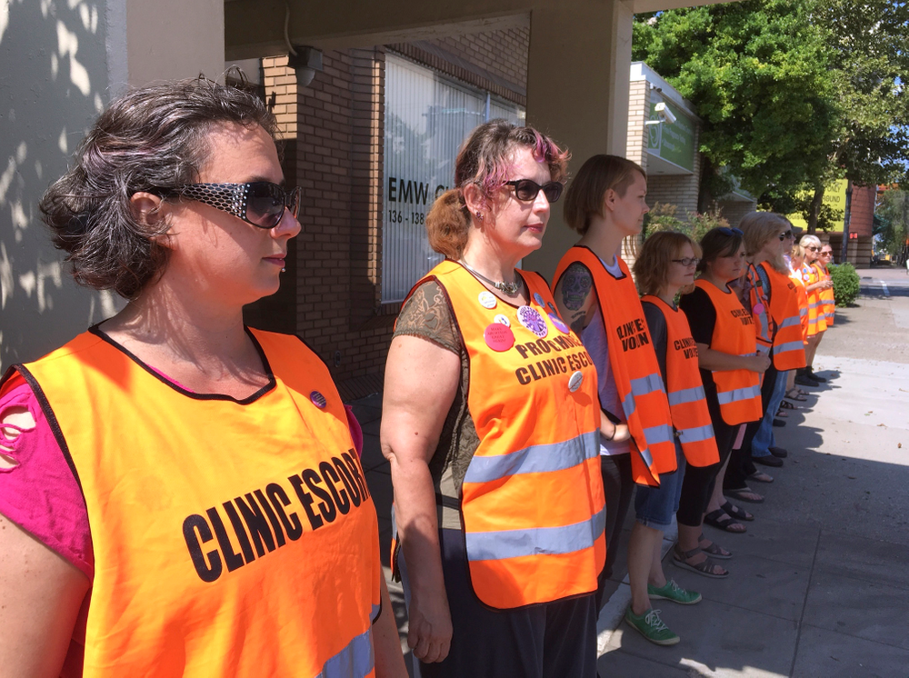 FILE - In this July 17, 2017 file photo, escort volunteers line up outside the EMW Women's Surgical Center in Louisville, Ky. Kentucky's Republican governor has signed a measure putting new restrictions on abortion, and his lawyers filed a response to a lawsuit already aimed at blocking it, Tuesday, March 19, 2019. Before Gov. Matt Bevin signed the measure, the American Civil Liberties Union challenged the legislation in a federal lawsuit. The new law bans abortion for women seeking to end their pregnancies because of the gender, race or disability of the fetus. (AP Photo/Dylan Lovan, File) FILE - In this July 17, 2017 file photo, escort volunteers line up outside the EMW Women's Surgical Center in Louisville, Ky. Kentucky's Republican governor has signed a measure putting new restrictions on abortion, and his lawyers filed a response to a lawsuit already aimed at blocking it, Tuesday, March 19, 2019. Before Gov. Matt Bevin signed the measure, the American Civil Liberties Union challenged the legislation in a federal lawsuit. The new law bans abortion for women seeking to end their pregnancies because of the gender, race or disability of the fetus. (AP Photo/Dylan Lovan, File)