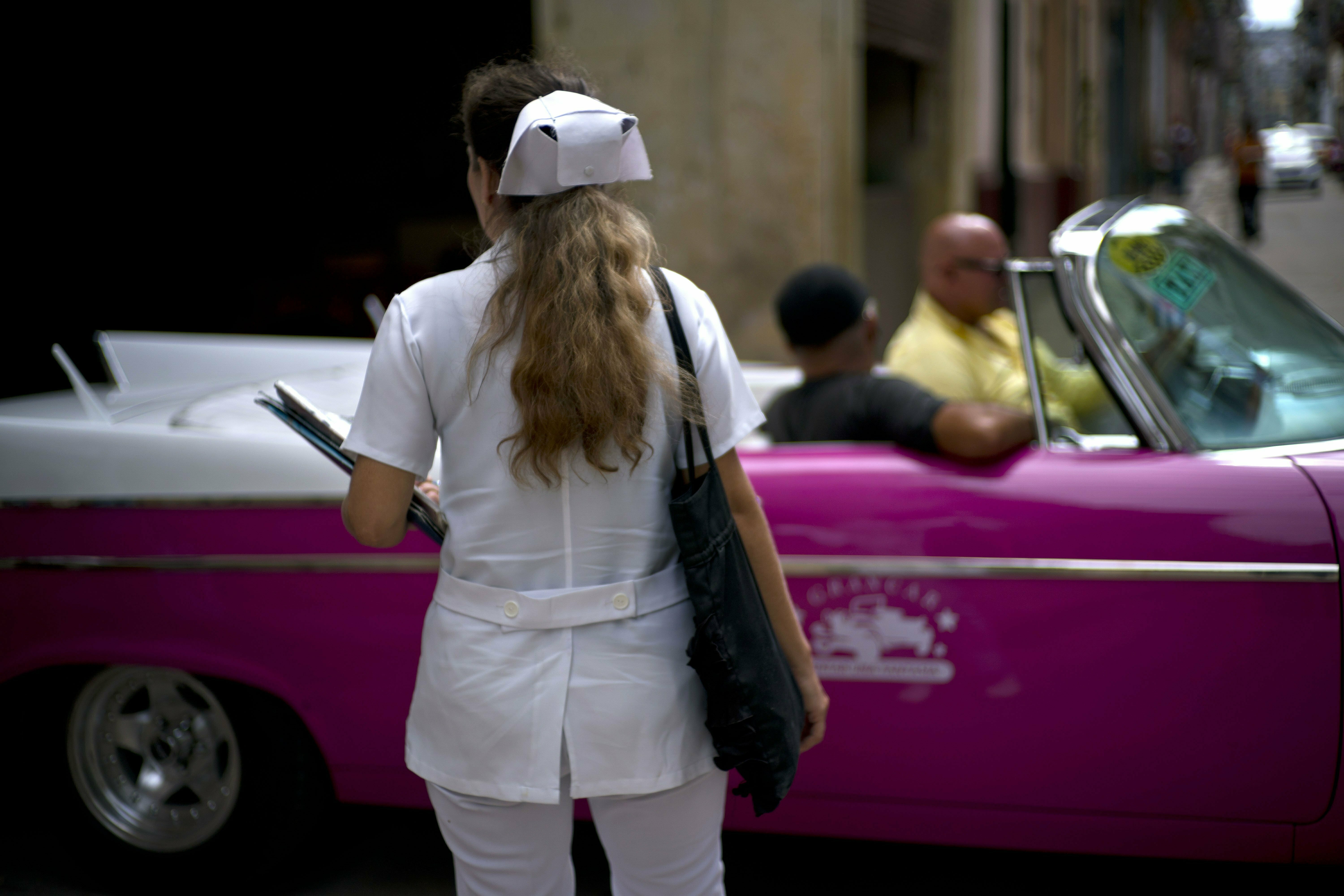 A nurse walks down the street where a classic American car carries tourists in Havana, Cuba, Wednesday, April 10, 2019. Communist Party leader Raúl Castro warned Cubans on Wednesday that they should brace for worsening shortages due to Trump administration policies, but said the island won't return to the extreme deprivation of the post-Soviet period. (AP Photo/Ramon Espinosa) A nurse walks down the street where a classic American car carries tourists in Havana, Cuba, Wednesday, April 10, 2019. Communist Party leader Raúl Castro warned Cubans on Wednesday that they should brace for worsening shortages due to Trump administration policies, but said the island won't return to the extreme deprivation of the post-Soviet period. (AP Photo/Ramon Espinosa)