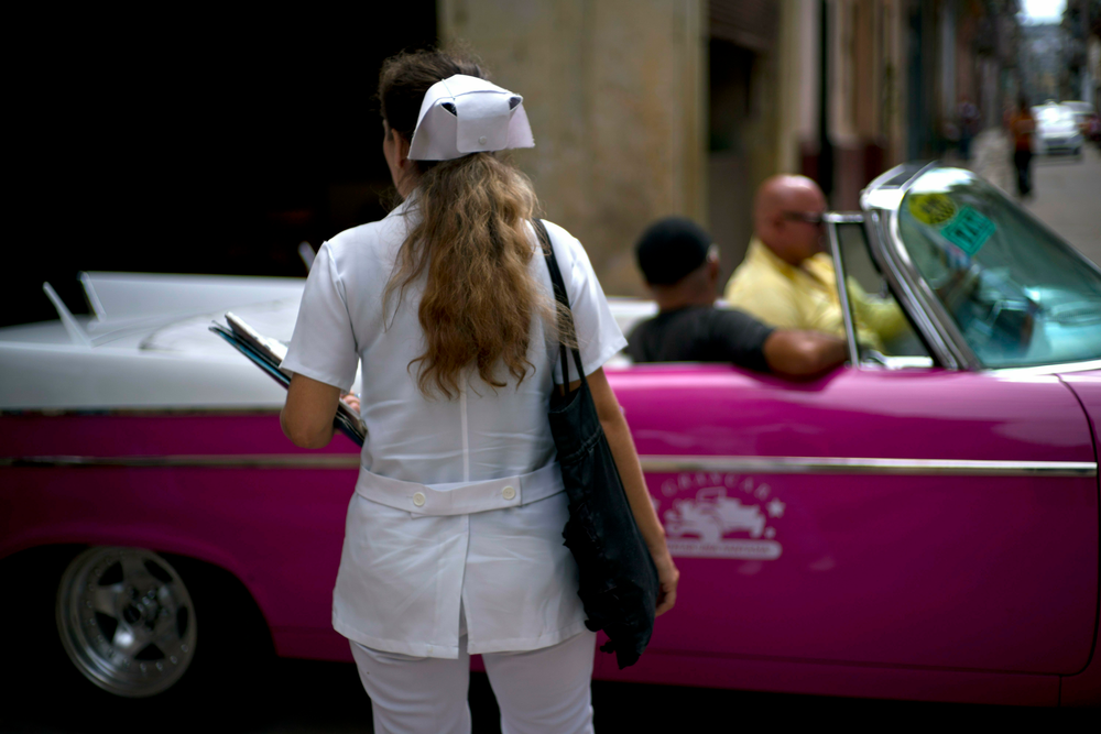 A nurse walks down the street where a classic American car carries tourists in Havana, Cuba, Wednesday, April 10, 2019. Communist Party leader Raúl Castro warned Cubans on Wednesday that they should brace for worsening shortages due to Trump administration policies, but said the island won't return to the extreme deprivation of the post-Soviet period. (AP Photo/Ramon Espinosa) A nurse walks down the street where a classic American car carries tourists in Havana, Cuba, Wednesday, April 10, 2019. Communist Party leader Raúl Castro warned Cubans on Wednesday that they should brace for worsening shortages due to Trump administration policies, but said the island won't return to the extreme deprivation of the post-Soviet period. (AP Photo/Ramon Espinosa)