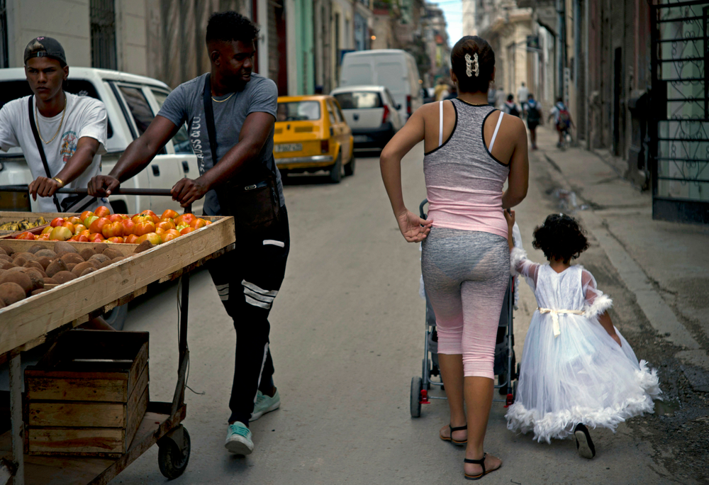 A girl in an angel costume walks with her family past vegetable vendors in Havana, Cuba, Wednesday, April 10, 2019. Communist Party leader Raúl Castro warned Cubans on Wednesday that they should brace for worsening shortages due to Trump administration policies, but said the island won't return to the extreme deprivation of the post-Soviet period. (AP Photo/Ramon Espinosa) A girl in an angel costume walks with her family past vegetable vendors in Havana, Cuba, Wednesday, April 10, 2019. Communist Party leader Raúl Castro warned Cubans on Wednesday that they should brace for worsening shortages due to Trump administration policies, but said the island won't return to the extreme deprivation of the post-Soviet period. (AP Photo/Ramon Espinosa)