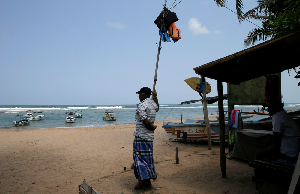 In this Friday, May 10, 2019, photo, a Sri Lankan reef safari boat operator stands on an empty beach in Hikkaduwa, Sri Lanka. Sri Lanka was the Lonely Planet guide’s top travel destination for 2019, but since the Easter Sunday attacks on churches and luxury hotels, foreign tourists have fled. Hikkaduwa, in the south west, used to be top tourist attraction for the strong waves that were perfect for board-surfing and sparkling clear waters perfect for snorkeling. Today, of the 27 hotels, a very few are still open while most of others along with the eateries lining the six kilometer stretch of palm-fringed beach, are closed. (AP Photo/Eranga Jayawardena) In this Friday, May 10, 2019, photo, a Sri Lankan reef safari boat operator stands on an empty beach in Hikkaduwa, Sri Lanka. Sri Lanka was the Lonely Planet guide’s top travel destination for 2019, but since the Easter Sunday attacks on churches and luxury hotels, foreign tourists have fled. Hikkaduwa, in the south west, used to be top tourist attraction for the strong waves that were perfect for board-surfing and sparkling clear waters perfect for snorkeling. Today, of the 27 hotels, a very few are still open while most of others along with the eateries lining the six kilometer stretch of palm-fringed beach, are closed. (AP Photo/Eranga Jayawardena)