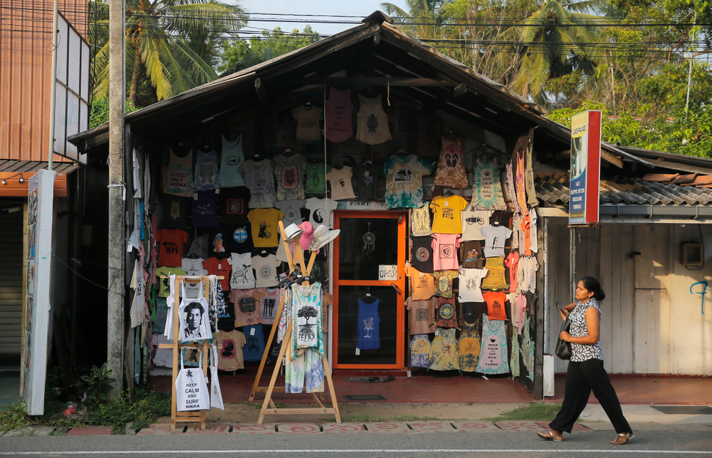 In this Friday, May 10, 2019, photo, a Sri Lankan walks past a souvenir shop in Hikkaduwa, Sri Lanka. Sri Lanka was the Lonely Planet guide’s top travel destination for 2019, but since the Easter Sunday attacks on churches and luxury hotels, foreign tourists have fled. Hikkaduwa, in the south west, used to be top tourist attraction for the strong waves that were perfect for board-surfing and sparkling clear waters perfect for snorkeling. Today, of the 27 hotels, a very few are still open while most of others along with the eateries lining the six kilometer stretch of palm-fringed beach, are closed. (AP Photo/Eranga Jayawardena) In this Friday, May 10, 2019, photo, a Sri Lankan walks past a souvenir shop in Hikkaduwa, Sri Lanka. Sri Lanka was the Lonely Planet guide’s top travel destination for 2019, but since the Easter Sunday attacks on churches and luxury hotels, foreign tourists have fled. Hikkaduwa, in the south west, used to be top tourist attraction for the strong waves that were perfect for board-surfing and sparkling clear waters perfect for snorkeling. Today, of the 27 hotels, a very few are still open while most of others along with the eateries lining the six kilometer stretch of palm-fringed beach, are closed. (AP Photo/Eranga Jayawardena)