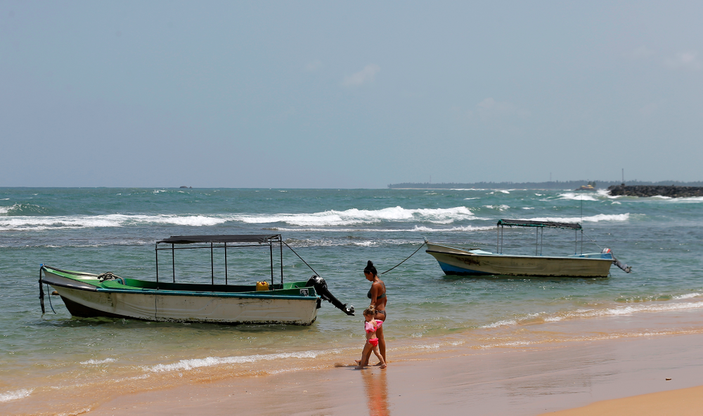 In this Friday, May 10, 2019, photo, a Ukrainian woman and a child walk past glass bottom boats, used for watching coral reefs, on a beach in Hikkaduwa, Sri Lanka. Sri Lanka was the Lonely Planet guide’s top travel destination for 2019, but since the Easter Sunday attacks on churches and luxury hotels, foreign tourists have fled. Hikkaduwa, in the south west, used to be top tourist attraction for the strong waves that were perfect for board-surfing and sparkling clear waters perfect for snorkeling. Today, of the 27 hotels, a very few are still open while most of others along with the eateries lining the six kilometer stretch of palm-fringed beach, are closed. (AP Photo/Eranga Jayawardena) In this Friday, May 10, 2019, photo, a Ukrainian woman and a child walk past glass bottom boats, used for watching coral reefs, on a beach in Hikkaduwa, Sri Lanka. Sri Lanka was the Lonely Planet guide’s top travel destination for 2019, but since the Easter Sunday attacks on churches and luxury hotels, foreign tourists have fled. Hikkaduwa, in the south west, used to be top tourist attraction for the strong waves that were perfect for board-surfing and sparkling clear waters perfect for snorkeling. Today, of the 27 hotels, a very few are still open while most of others along with the eateries lining the six kilometer stretch of palm-fringed beach, are closed. (AP Photo/Eranga Jayawardena)