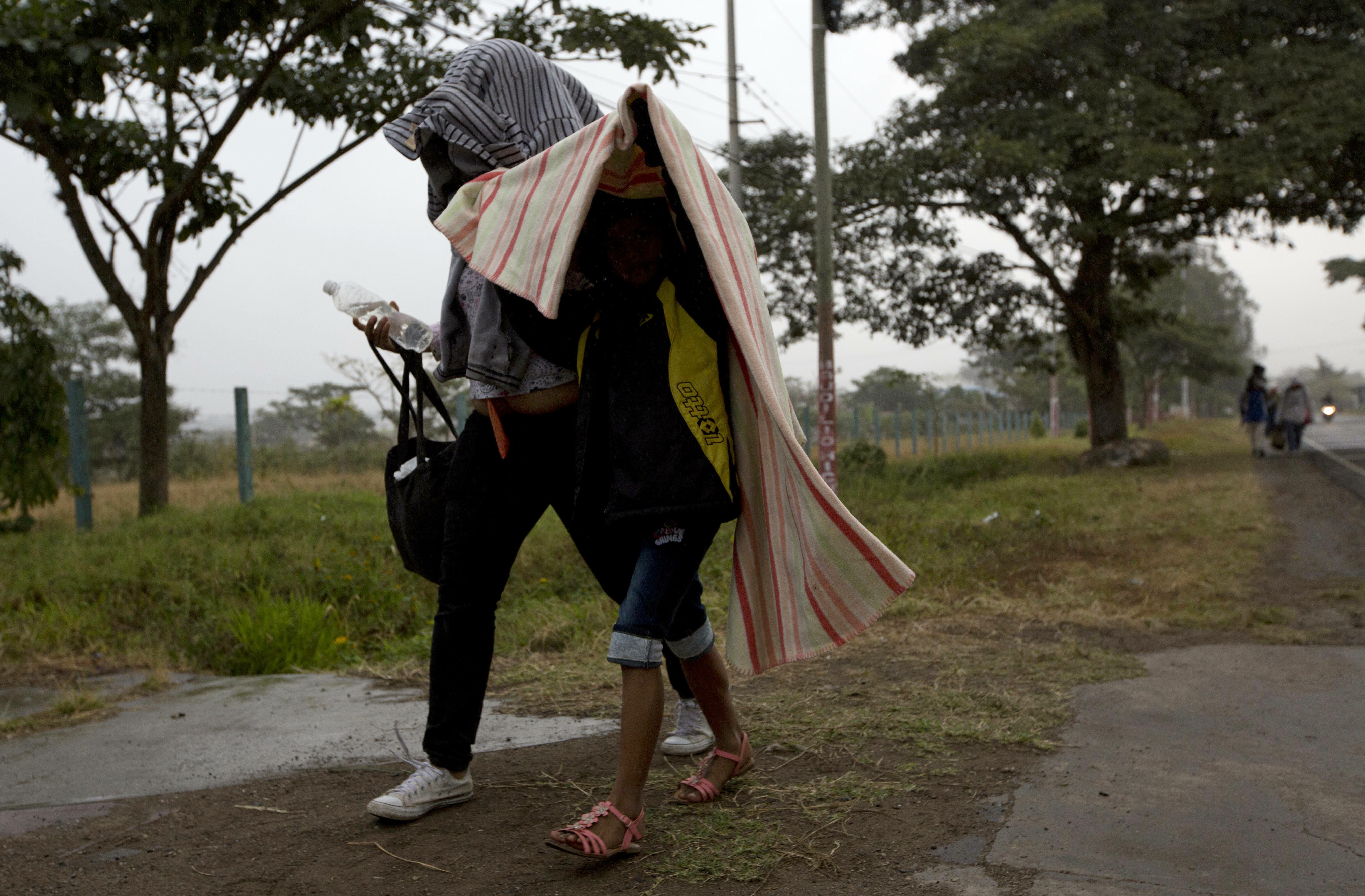Honduran migrants shield themselves from a light rain as they walk north along the roadside through Esquipulas, Guatemala, early Wednesday, Jan. 16, 2019. The latest caravan of Honduran migrants hoping to reach the U.S. has crossed into Guatemala. (AP Photo/Moises Castillo) Honduran migrants shield themselves from a light rain as they walk north along the roadside through Esquipulas, Guatemala, early Wednesday, Jan. 16, 2019. The latest caravan of Honduran migrants hoping to reach the U.S. has crossed into Guatemala. (AP Photo/Moises Castillo)