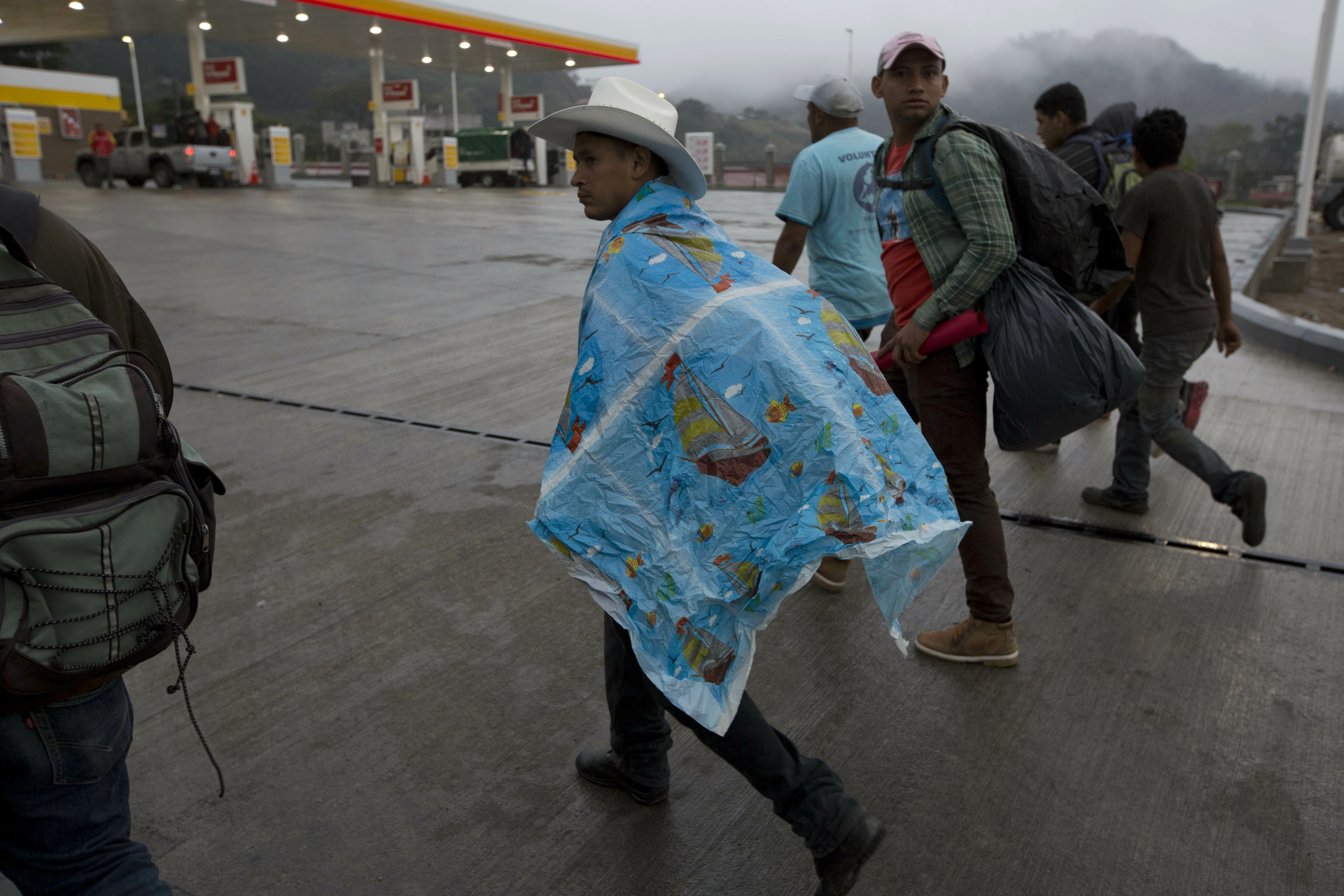 A Honduran migrant shields himself from a light rain as he walks north with other migrants along the roadside through Esquipulas, Guatemala, early Wednesday, Jan. 16, 2019. The latest caravan of Honduran migrants hoping to reach the U.S. has crossed into Guatemala. (AP Photo/Moises Castillo) A Honduran migrant shields himself from a light rain as he walks north with other migrants along the roadside through Esquipulas, Guatemala, early Wednesday, Jan. 16, 2019. The latest caravan of Honduran migrants hoping to reach the U.S. has crossed into Guatemala. (AP Photo/Moises Castillo)