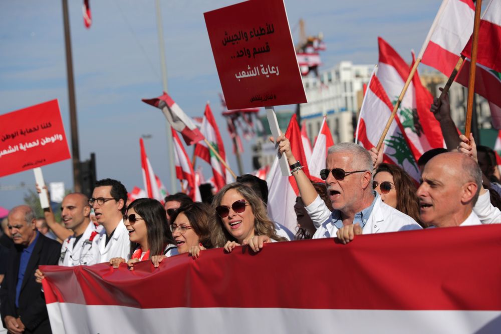 Anti-government doctors shout slogans during separate civil parade at the Martyr square, in downtown Beirut, Lebanon, Friday, Nov. 22, 2019. Protesters gathered for alternative independence celebrations, converging by early afternoon on Martyrs’ Square in central Beirut, which used to be the traditional location of the official parade. Protesters have occupied the area, closing it off to traffic since mid-October. (AP Photo/Hassan Ammar) Anti-government doctors shout slogans during separate civil parade at the Martyr square, in downtown Beirut, Lebanon, Friday, Nov. 22, 2019. Protesters gathered for alternative independence celebrations, converging by early afternoon on Martyrs’ Square in central Beirut, which used to be the traditional location of the official parade. Protesters have occupied the area, closing it off to traffic since mid-October. (AP Photo/Hassan Ammar)
