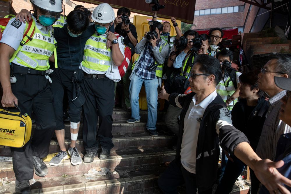 President of the Polytechnic University Jin-Guang Teng, second from right, looks as an injured protester is helped by medics to leave the campus in Hong Kong on Wednesday, Nov. 20, 2019. A small group of protesters refused to leave Hong Kong Polytechnic University, the remnants of hundreds who took over the campus for several days. They won't leave because they would face arrest. Police have set up a cordon around the area to prevent anyone from escaping. (AP Photo/Ng Han Guan) President of the Polytechnic University Jin-Guang Teng, second from right, looks as an injured protester is helped by medics to leave the campus in Hong Kong on Wednesday, Nov. 20, 2019. A small group of protesters refused to leave Hong Kong Polytechnic University, the remnants of hundreds who took over the campus for several days. They won't leave because they would face arrest. Police have set up a cordon around the area to prevent anyone from escaping. (AP Photo/Ng Han Guan)