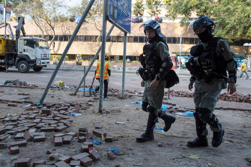 Riot police pass as workers clear the road in front of the Polytechnic University in Hong Kong on Wednesday, Nov. 20, 2019. A small group of protesters refused to leave Hong Kong Polytechnic University, the remnants of hundreds who took over the campus for several days. They won't leave because they would face arrest. Police have set up a cordon around the area to prevent anyone from escaping. (AP Photo/Ng Han Guan) Riot police pass as workers clear the road in front of the Polytechnic University in Hong Kong on Wednesday, Nov. 20, 2019. A small group of protesters refused to leave Hong Kong Polytechnic University, the remnants of hundreds who took over the campus for several days. They won't leave because they would face arrest. Police have set up a cordon around the area to prevent anyone from escaping. (AP Photo/Ng Han Guan)