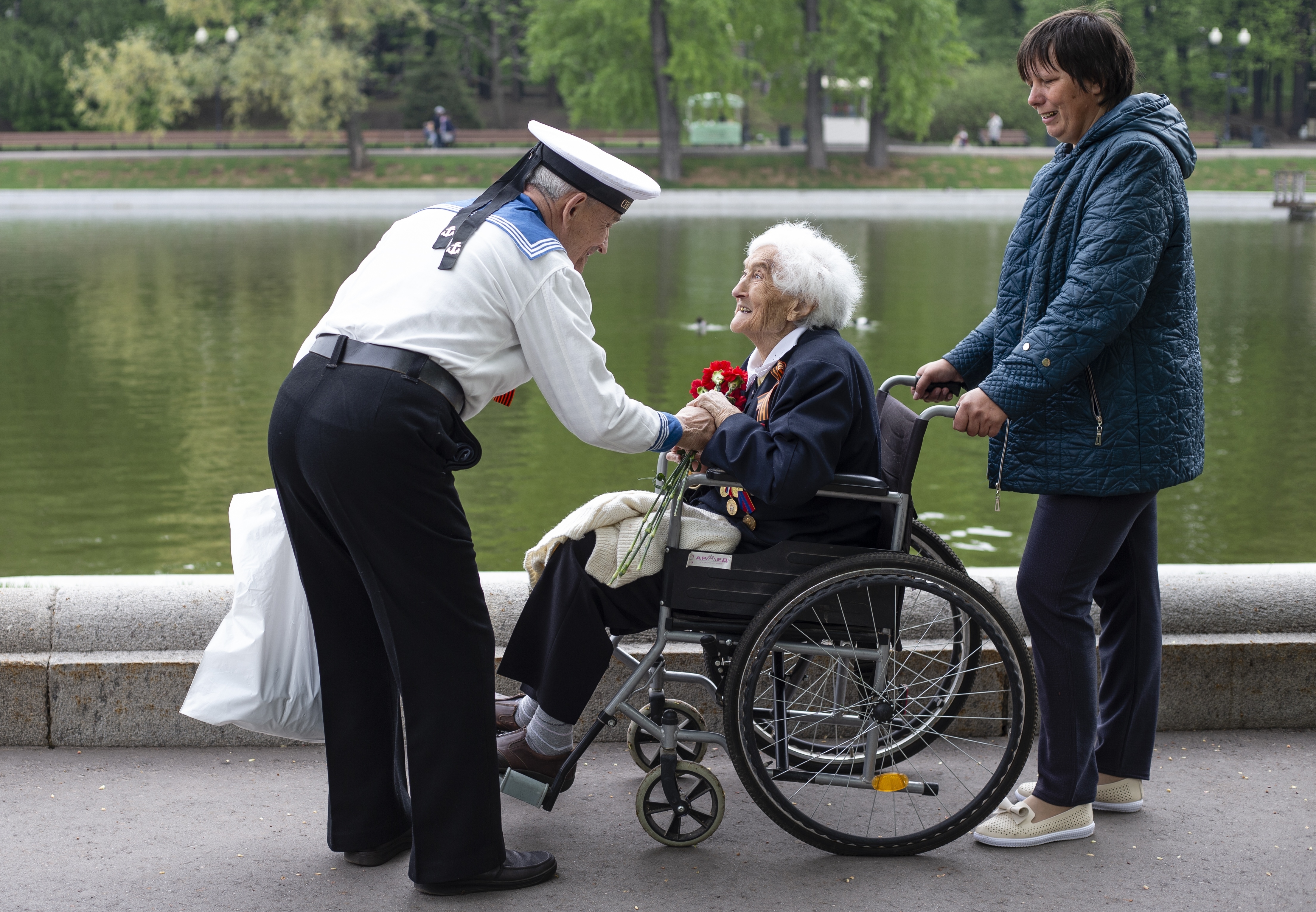 Victor Novopashin, 87, a Russian WWII veteran, left, greets Maria Kanushkina, 95, center, also a Russian WWII veteran celebrating 74 years since the victory in WWII in Gorky Park in Moscow, Russia, Thursday, May 9, 2019. (AP Photo/Alexander Zemlianichenko Jr.)