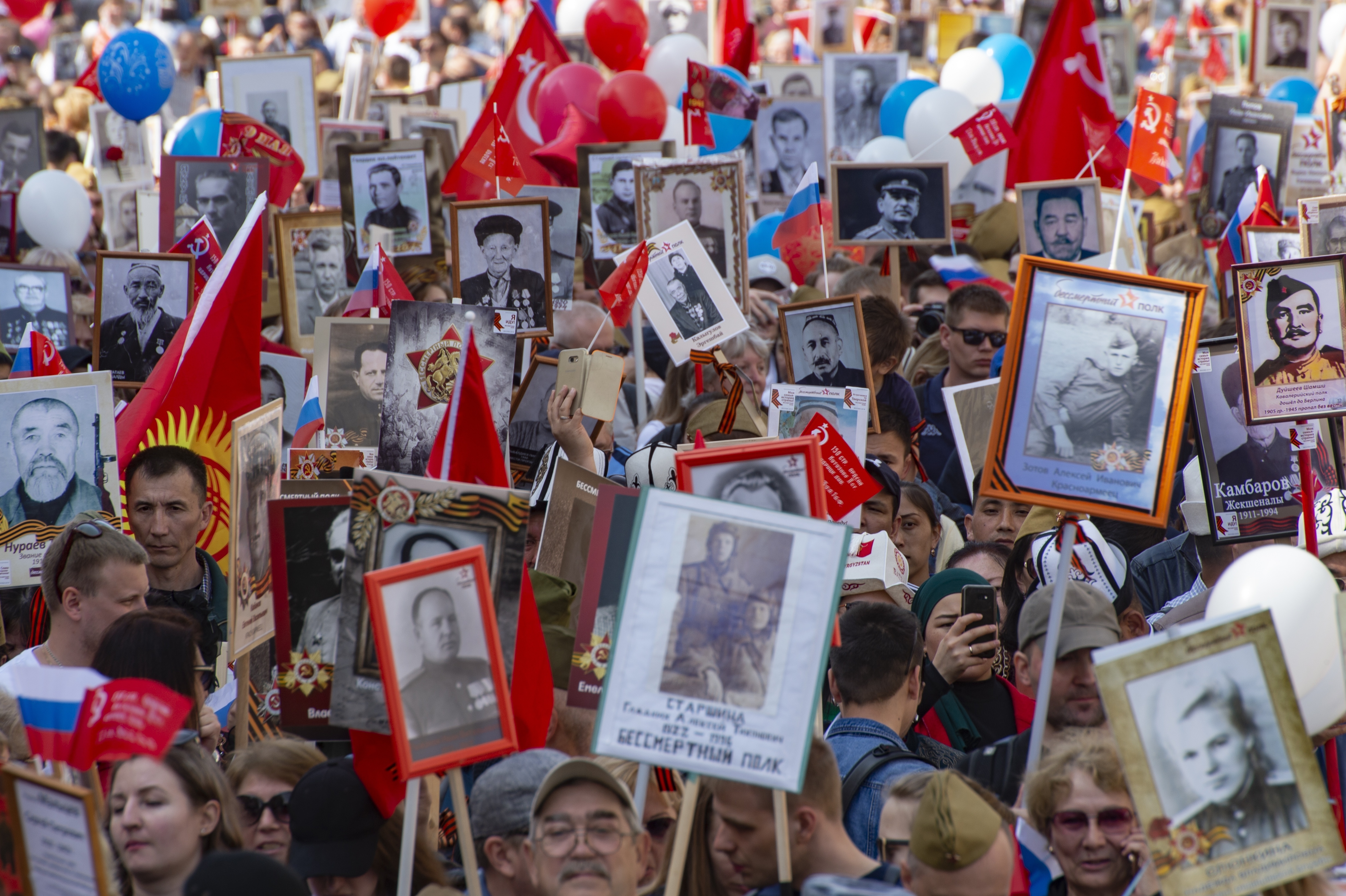 People carry portraits of relatives who fought in World War II, and Russian and Soviet flags, during the Immortal Regiment march through the main street toward Red Square in Moscow, Russia, Thursday, May 9, 2019, celebrating 74 years since the end of WWII and the defeat of Nazi Germany. (AP Photo/Dmitry Serebryakov)