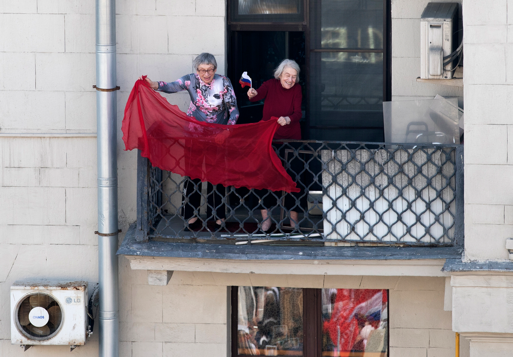 Two elderly women wave a red flag as people carry portraits of relatives who fought in World War II, and Russian and Soviet flags, during the Immortal Regiment march through the main street toward Red Square celebrating 74 years since the victory in WWII in Red Square in Moscow, Russia, Thursday, May 9, 2019. (AP Photo/Denis Tyrin) Two elderly women wave a red flag as people carry portraits of relatives who fought in World War II, and Russian and Soviet flags, during the Immortal Regiment march through the main street toward Red Square celebrating 74 years since the victory in WWII in Red Square in Moscow, Russia, Thursday, May 9, 2019. (AP Photo/Denis Tyrin)