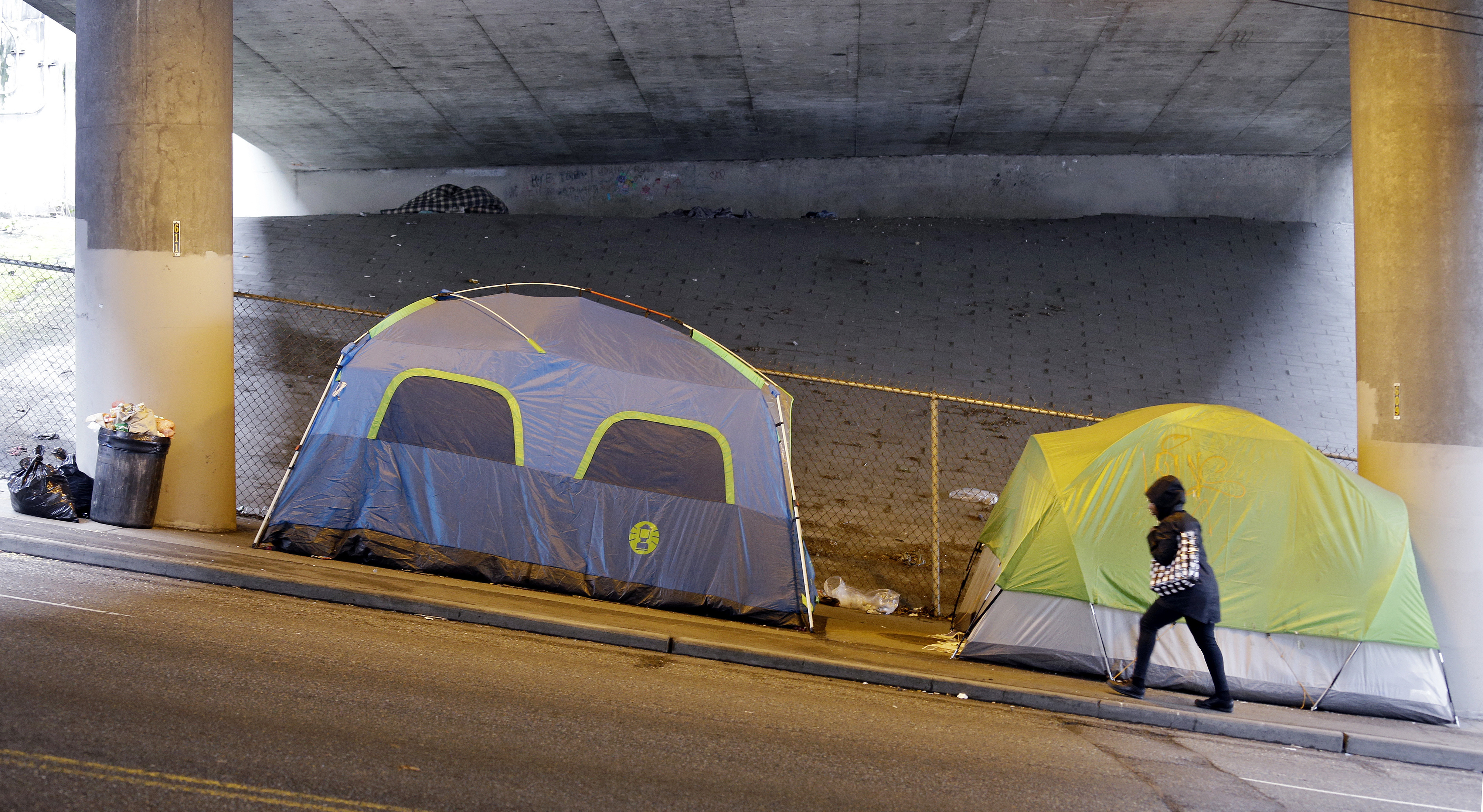 FILE - In this March 8, 2017 file photo, a person walks up a hill next to tents lined up beneath a highway and adjacent to downtown Seattle. Microsoft pledged $500 million to address homelessness and develop affordable housing in response to the Seattle region's widening affordability gap. The company plans a news conference, Thursday, Jan. 17, 2019. (AP Photo/Elaine Thompson, File) FILE - In this March 8, 2017 file photo, a person walks up a hill next to tents lined up beneath a highway and adjacent to downtown Seattle. Microsoft pledged $500 million to address homelessness and develop affordable housing in response to the Seattle region's widening affordability gap. The company plans a news conference, Thursday, Jan. 17, 2019. (AP Photo/Elaine Thompson, File)