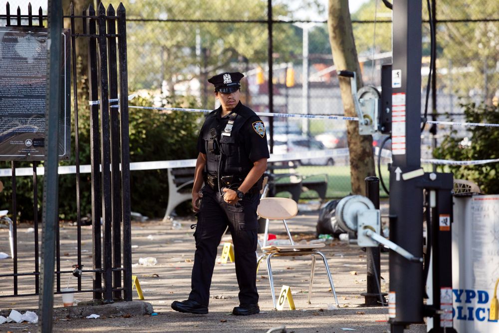 A police officer walks by yellow evidence markers at a playground in the Brownsville neighborhood in the Brooklyn borough of New York, Sunday, July 28, 2019. Police said, one man was killed and at least 11 others were injured in a shooting late Saturday night at the park. (AP Photo/Mark Lennihan) A police officer walks by yellow evidence markers at a playground in the Brownsville neighborhood in the Brooklyn borough of New York, Sunday, July 28, 2019. Police said, one man was killed and at least 11 others were injured in a shooting late Saturday night at the park. (AP Photo/Mark Lennihan)