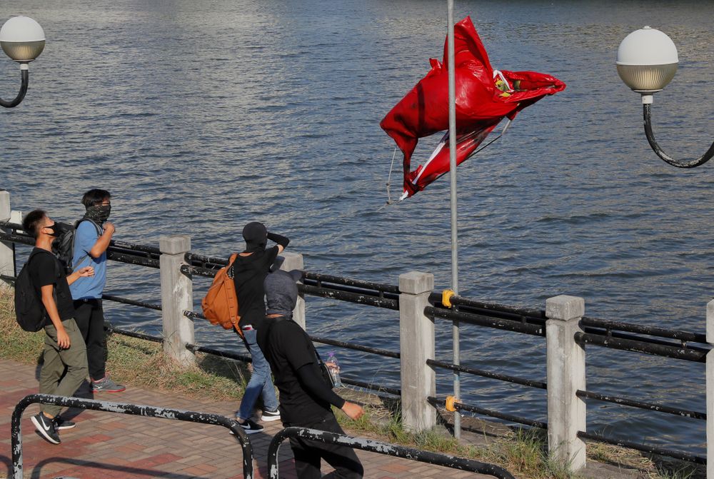Protesters throw a Chinese national flag into the river after vandalizing it Sunday, Sept. 22, 2019, in Hong Kong. Hong Kong's pro-democracy protests, now in their fourth month, have often descended into violence. A hardcore group of the protesters says the extreme actions are needed to get the government's attention. (AP Photo/Kin Cheung) Protesters throw a Chinese national flag into the river after vandalizing it Sunday, Sept. 22, 2019, in Hong Kong. Hong Kong's pro-democracy protests, now in their fourth month, have often descended into violence. A hardcore group of the protesters says the extreme actions are needed to get the government's attention. (AP Photo/Kin Cheung)