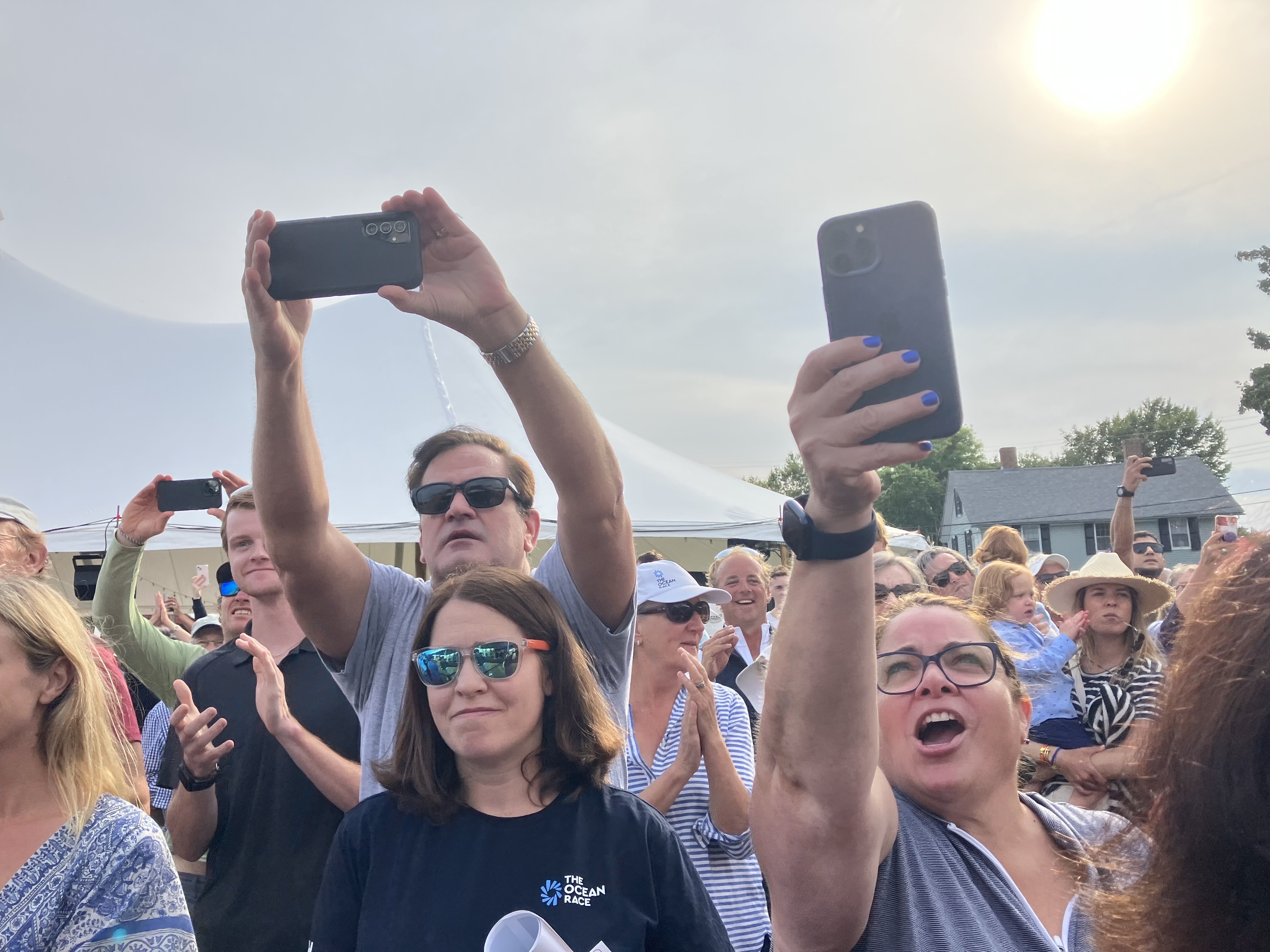 Fans raise their phones and voices as they cheer the 11th Hour Racing team at a community celebration in downtown Newport on Friday, August 24, 2023.