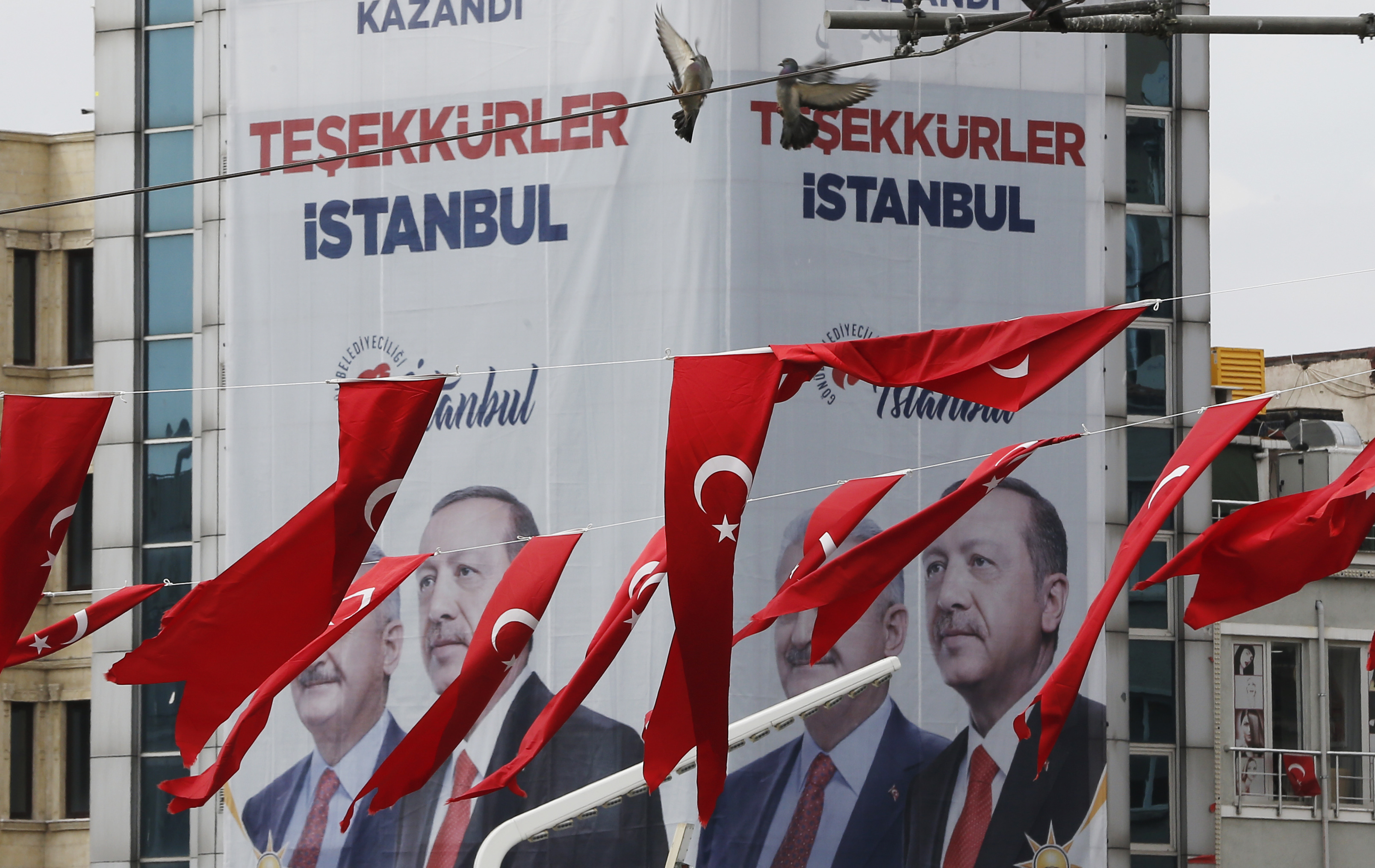 In this Thursday, April 4, 2019 photo, Turkish flags fly in Istanbul Taksim's square while in the background posters showing Binali Yildirim, left, the mayoral candidate for Istanbul of Turkey's President Recep Tayyip Erdogan's ruling Justice and Development Party's (AKP) and Erdogan are seen. The posters reads in Turkish: 'Thank you, Istanbul'. The mood among opposition supporters in Turkey's biggest city is one of jubilation but also worry - fear that their win in Istanbul's mayoral race could be overturned in a recount taking place after the ruling party challenged the election results. (AP Photo/Lefteris Pitarakis) In this Thursday, April 4, 2019 photo, Turkish flags fly in Istanbul Taksim's square while in the background posters showing Binali Yildirim, left, the mayoral candidate for Istanbul of Turkey's President Recep Tayyip Erdogan's ruling Justice and Development Party's (AKP) and Erdogan are seen. The posters reads in Turkish: 'Thank you, Istanbul'. The mood among opposition supporters in Turkey's biggest city is one of jubilation but also worry - fear that their win in Istanbul's mayoral race could be overturned in a recount taking place after the ruling party challenged the election results. (AP Photo/Lefteris Pitarakis)
