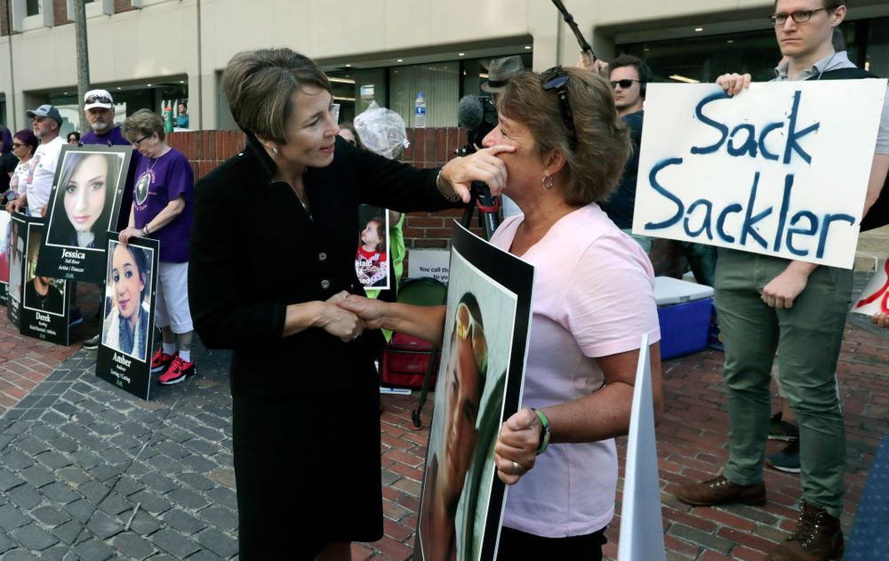 Massachusetts Attorney General Maura Healey, left, wipes a tear from the face of Wendy Werbiskis, of East Hampton, Mass., one of the protesters gathered on Friday, Aug. 2, 2019, outside a courthouse in Boston, where a judge was to hear arguments in state's lawsuit against Purdue Pharma over its role in the national drug epidemic. Organizers said they wanted to continue to put pressure on the Connecticut pharmaceutical company and the Sackler family that owns it. Werbiskis lost her son to an overdose two years ago. (AP Photo/Charles Krupa) Massachusetts Attorney General Maura Healey, left, wipes a tear from the face of Wendy Werbiskis, of East Hampton, Mass., one of the protesters gathered on Friday, Aug. 2, 2019, outside a courthouse in Boston, where a judge was to hear arguments in state's lawsuit against Purdue Pharma over its role in the national drug epidemic. Organizers said they wanted to continue to put pressure on the Connecticut pharmaceutical company and the Sackler family that owns it. Werbiskis lost her son to an overdose two years ago. (AP Photo/Charles Krupa)