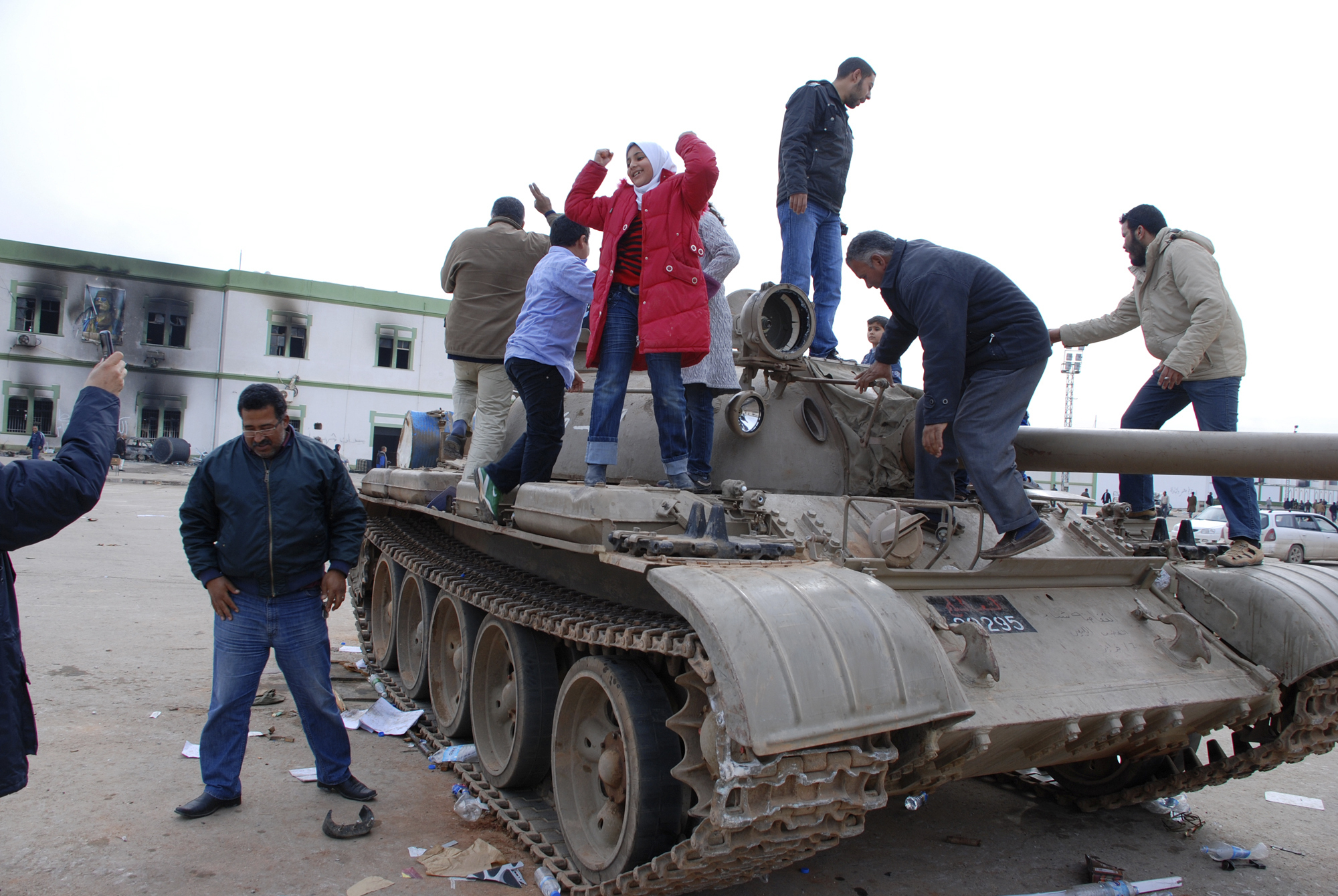 FILE - In this Feb. 21, 2011 file photo, people stand on a tank inside a security forces compound in the eastern Libyan city of Benghazi. Libyans are celebrating the eighth anniversary of their 2011 uprising that led to the overthrow and killing of longtime dictator Moammar Gadhafi, although the intensity of the festivities is underlining the split between the country’s east and west. Hundreds of people reveled Sunday in the western cities of Tripoli, Misrata and Zawiya, where bands played and flags lined the streets. (AP Photo/Alagur, File) FILE - In this Feb. 21, 2011 file photo, people stand on a tank inside a security forces compound in the eastern Libyan city of Benghazi. Libyans are celebrating the eighth anniversary of their 2011 uprising that led to the overthrow and killing of longtime dictator Moammar Gadhafi, although the intensity of the festivities is underlining the split between the country’s east and west. Hundreds of people reveled Sunday in the western cities of Tripoli, Misrata and Zawiya, where bands played and flags lined the streets. (AP Photo/Alagur, File)