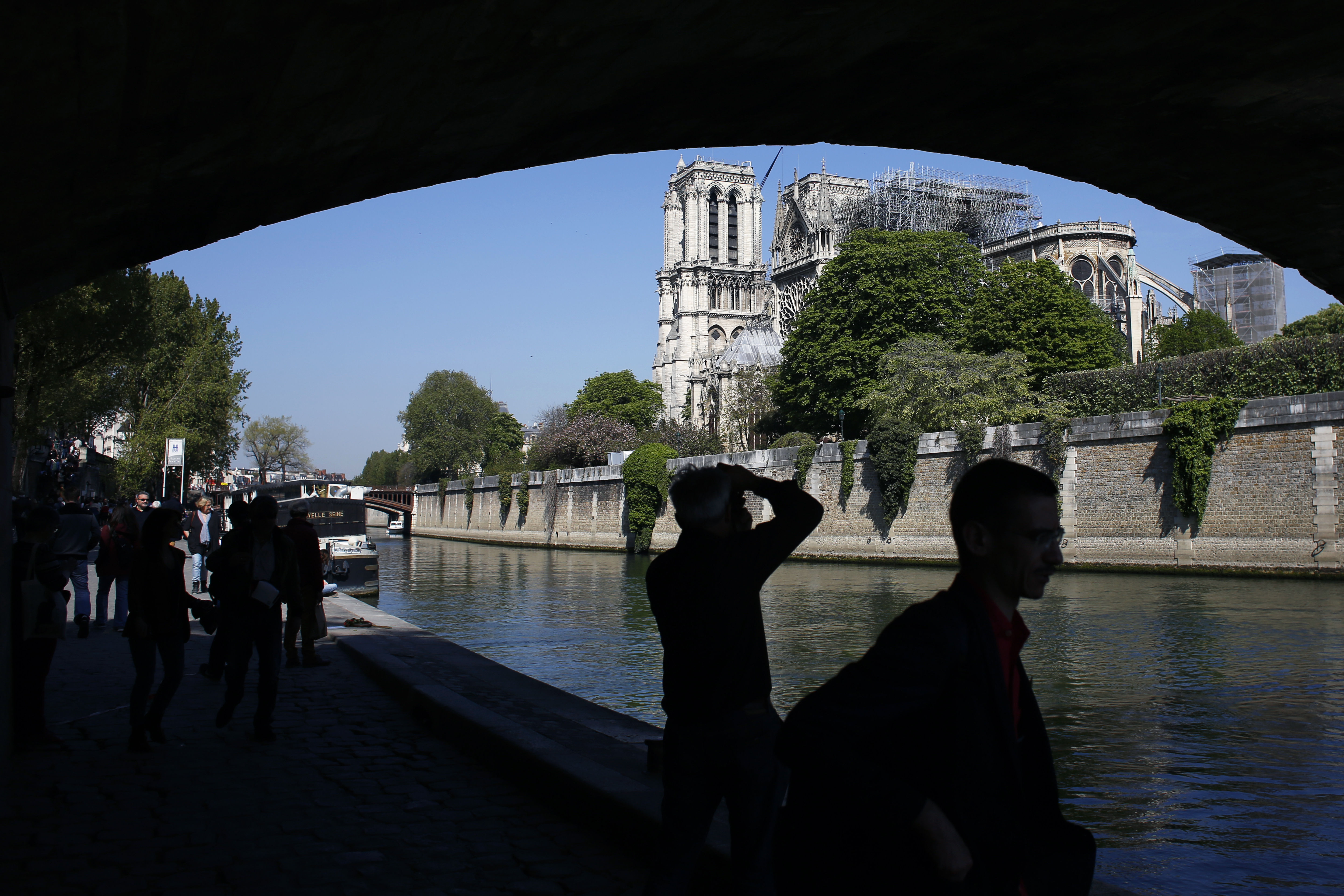 Tourists walk nearby Notre Dame cathedral, in Paris, Friday, April 19, 2019. Rebuilding Notre Dame, the 800-year-old Paris cathedral devastated by fire this week, will cost billions of dollars as architects, historians and artisans work to preserve the medieval landmark. (AP Photo/Thibault Camus) Tourists walk nearby Notre Dame cathedral, in Paris, Friday, April 19, 2019. Rebuilding Notre Dame, the 800-year-old Paris cathedral devastated by fire this week, will cost billions of dollars as architects, historians and artisans work to preserve the medieval landmark. (AP Photo/Thibault Camus)
