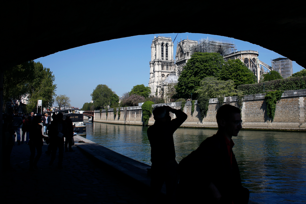 Tourists walk nearby Notre Dame cathedral, in Paris, Friday, April 19, 2019. Rebuilding Notre Dame, the 800-year-old Paris cathedral devastated by fire this week, will cost billions of dollars as architects, historians and artisans work to preserve the medieval landmark. (AP Photo/Thibault Camus) Tourists walk nearby Notre Dame cathedral, in Paris, Friday, April 19, 2019. Rebuilding Notre Dame, the 800-year-old Paris cathedral devastated by fire this week, will cost billions of dollars as architects, historians and artisans work to preserve the medieval landmark. (AP Photo/Thibault Camus)