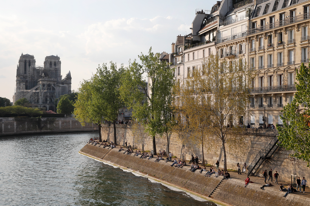 People enjoy the sun next the Notre Dame Cathedral along the Seine river in Paris, Friday, April 19, 2019. Rebuilding Notre Dame, the 800-year-old Paris cathedral devastated by fire this week, will cost billions of dollars as architects, historians and artisans work to preserve the medieval landmark. (AP Photo/Michel Euler) People enjoy the sun next the Notre Dame Cathedral along the Seine river in Paris, Friday, April 19, 2019. Rebuilding Notre Dame, the 800-year-old Paris cathedral devastated by fire this week, will cost billions of dollars as architects, historians and artisans work to preserve the medieval landmark. (AP Photo/Michel Euler)