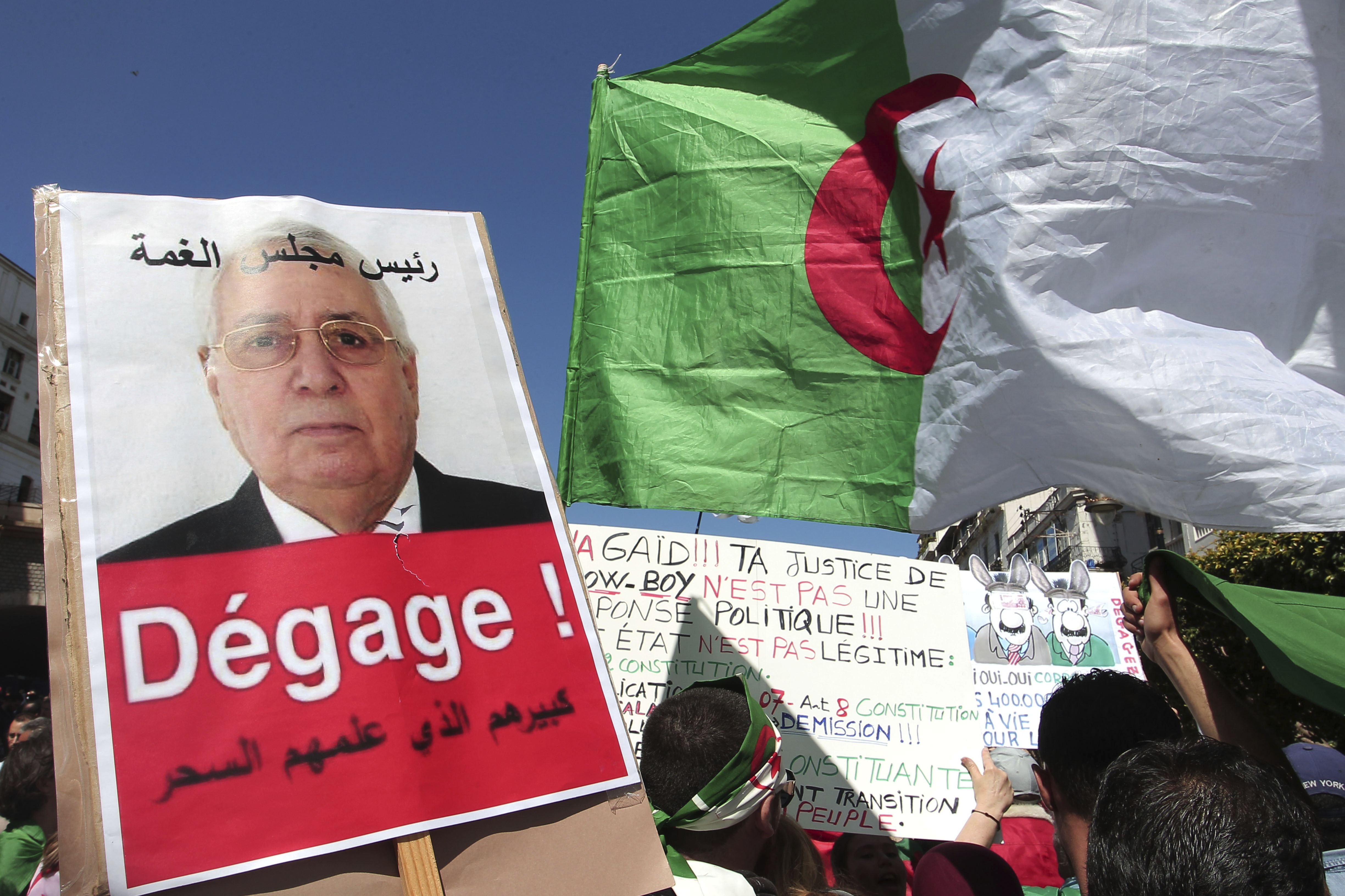A demonstrator holds a placard showing Abdelkader Bensalah and reading A demonstrator holds a placard showing Abdelkader Bensalah and reading