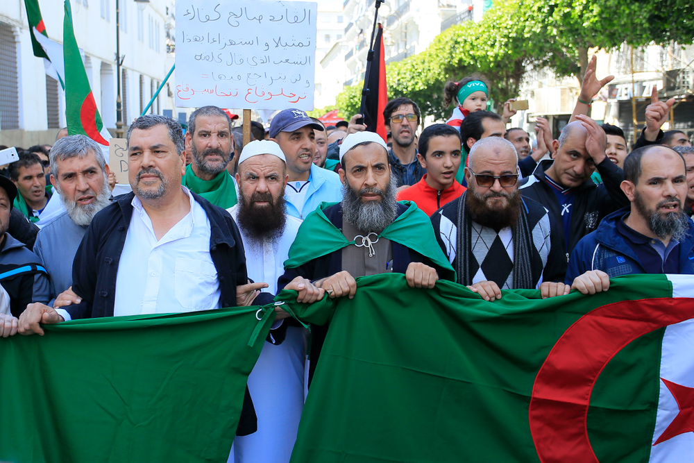 Demonstrators march with the Algerian flag during a protest in Algiers, Friday, April 26, 2019. Algerians are massing for a 10th week of protests against their country's ruling class, calling for the ex-president's brother to be put on trial. (AP Photo/Anis Belghoul) Demonstrators march with the Algerian flag during a protest in Algiers, Friday, April 26, 2019. Algerians are massing for a 10th week of protests against their country's ruling class, calling for the ex-president's brother to be put on trial. (AP Photo/Anis Belghoul)
