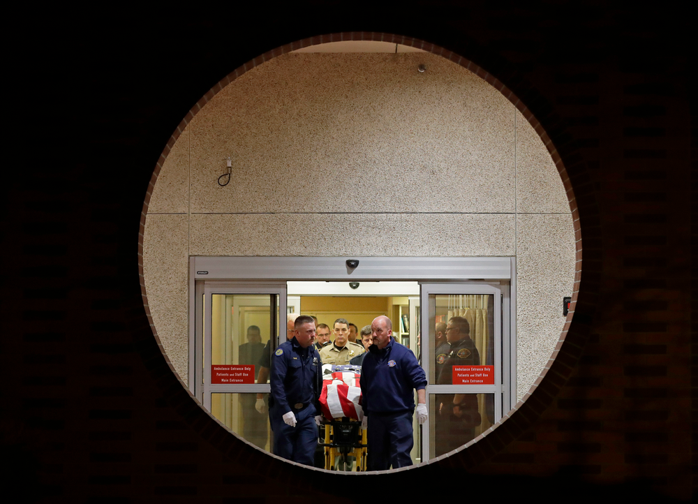 The body of a Kittitas County Sheriff's deputy is draped with a U.S. flag as it is carried out of Kittitas Valley Healthcare Hospital in the early morning hours of Wednesday, March 20, 2019, in Ellensburg, Wash., as seen through a large circular entry window. A sheriff's deputy was killed and a police officer was injured after an exchange of gunfire during an attempted traffic stop. (AP Photo/Ted S. Warren) The body of a Kittitas County Sheriff's deputy is draped with a U.S. flag as it is carried out of Kittitas Valley Healthcare Hospital in the early morning hours of Wednesday, March 20, 2019, in Ellensburg, Wash., as seen through a large circular entry window. A sheriff's deputy was killed and a police officer was injured after an exchange of gunfire during an attempted traffic stop. (AP Photo/Ted S. Warren)