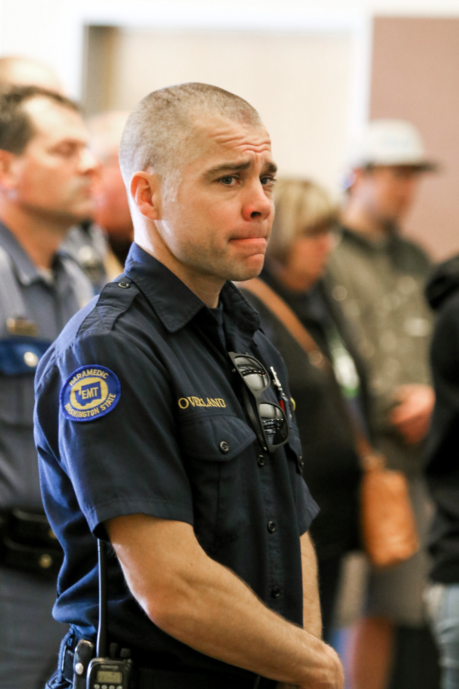 An EMT reacts while listening to Kittitas County Sheriff Gene Dana, not shown, speak at a news conference, Wednesday, March 20, 2019, in Ellensburg, Wash. about the death of Deputy Ryan Thompson, who was killed Tuesday evening when he and a Kittitas Police officer exchanged gunfire with a road-rage driving suspect in Kittitas, Wash. The driver of the vehicle was also shot and later died at a hospital. (Jake Green/The Daily Record via AP) An EMT reacts while listening to Kittitas County Sheriff Gene Dana, not shown, speak at a news conference, Wednesday, March 20, 2019, in Ellensburg, Wash. about the death of Deputy Ryan Thompson, who was killed Tuesday evening when he and a Kittitas Police officer exchanged gunfire with a road-rage driving suspect in Kittitas, Wash. The driver of the vehicle was also shot and later died at a hospital. (Jake Green/The Daily Record via AP)