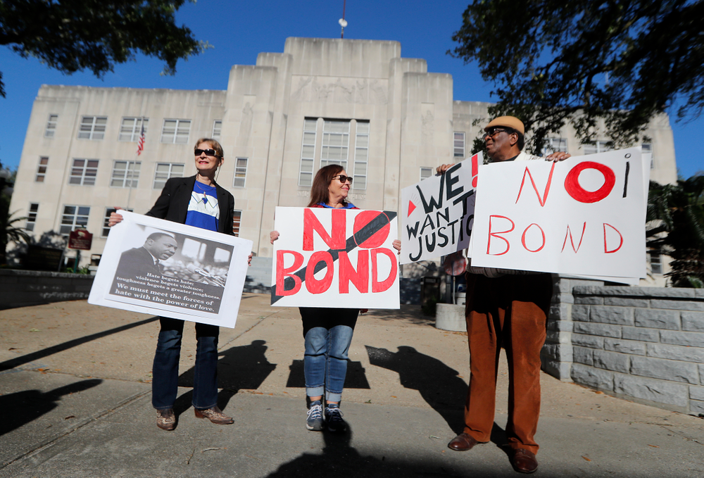 Wilfred Young, Agnes Courbille, left, and Karel Anne Zibe, center, of the St. Landry Parish branch of the NAACP, hold signs outside the St. Landry Parish courthouse during a bond hearing for Holden Matthews in Opelousas, La., Monday, April 15, 2019. Matthews, who is white, and is the son of a St. Landry Parish sheriff's deputy, was arrested Wednesday on three charges of arson of a religious building, and is the suspect in three recent arson fires that destroyed African American churches in Louisiana. (AP Photo/Gerald Herbert) Wilfred Young, Agnes Courbille, left, and Karel Anne Zibe, center, of the St. Landry Parish branch of the NAACP, hold signs outside the St. Landry Parish courthouse during a bond hearing for Holden Matthews in Opelousas, La., Monday, April 15, 2019. Matthews, who is white, and is the son of a St. Landry Parish sheriff's deputy, was arrested Wednesday on three charges of arson of a religious building, and is the suspect in three recent arson fires that destroyed African American churches in Louisiana. (AP Photo/Gerald Herbert)