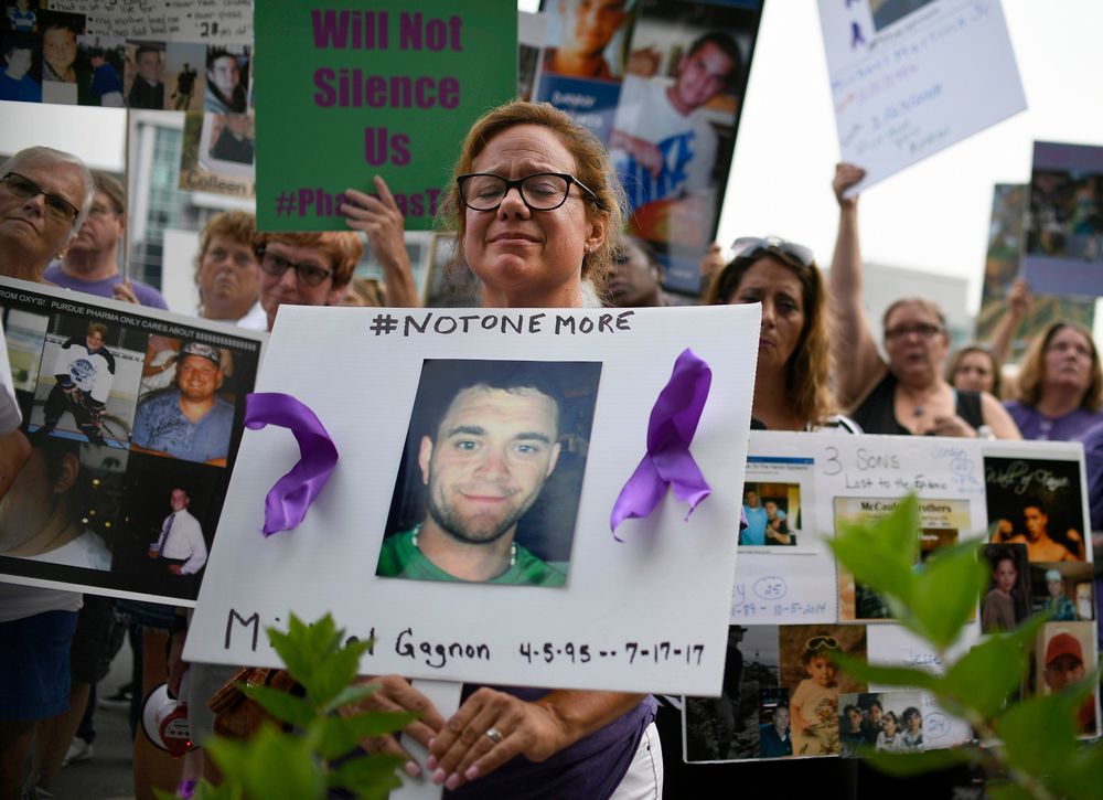FILE - In this Aug. 17, 2018 file photo, Christine Gagnon, of Southington, Conn., holds a sign during a protest with others who have lost loved ones to OxyContin and opioid overdoses, outside the Purdue Pharma headquarters in Stamford, Conn. Gagnon lost her son Michael 13 months earlier. Nearly ten years ago, the blockbuster painkiller OxyContin was reformulated to discourage abuse by snorting and injecting, but it's unclear whether the harder-to-abuse format has decreased cases of addiction, overdose and death. (AP Photo/Jessica Hill, File) FILE - In this Aug. 17, 2018 file photo, Christine Gagnon, of Southington, Conn., holds a sign during a protest with others who have lost loved ones to OxyContin and opioid overdoses, outside the Purdue Pharma headquarters in Stamford, Conn. Gagnon lost her son Michael 13 months earlier. Nearly ten years ago, the blockbuster painkiller OxyContin was reformulated to discourage abuse by snorting and injecting, but it's unclear whether the harder-to-abuse format has decreased cases of addiction, overdose and death. (AP Photo/Jessica Hill, File)