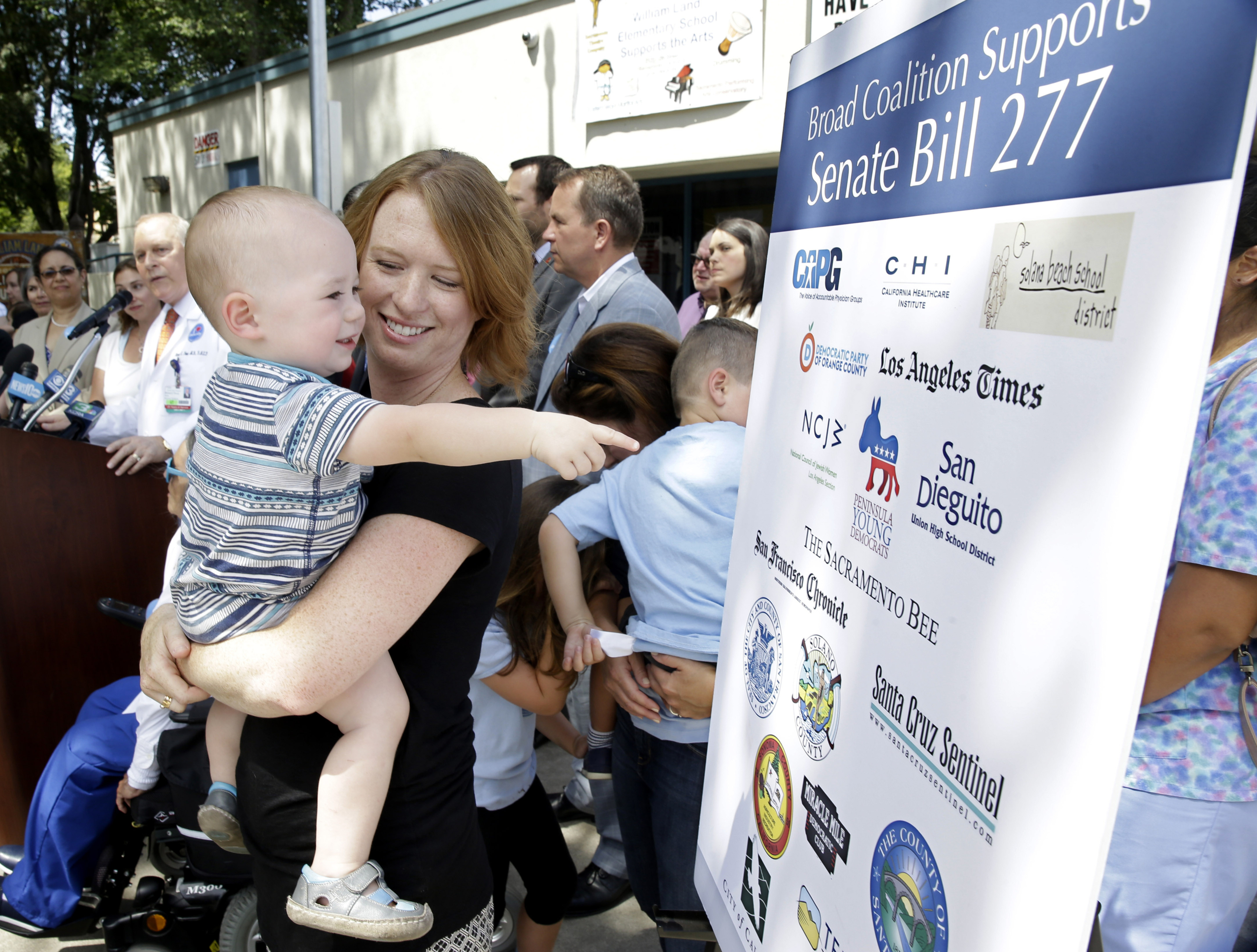 FILE - In this June 30, 2015, file photo, Jennifer Wonnacott holds her son, Gavin, as he points to a sign showing supporters of a measure requiring nearly all California school children to be vaccinated, at a news conference after the State Bill 277 was signed by Gov. Jerry Brown in Sacramento, Calif. State health officials say the number of measles cases in 2019 is up in California with cases stretching across 11 counties and affecting patients from 5 months to 55 years of age. Dr. Karen Smith, director of the California Department of Public Health, says more than 76% of patients were not vaccinated or didn't receive the recommended two doses of vaccine. Fourteen of those infected had traveled overseas to countries including Philippines, Thailand, India and Ukraine. Measles symptoms include high fever, a cough and a rash. (AP Photo/Rich Pedroncelli, File) FILE - In this June 30, 2015, file photo, Jennifer Wonnacott holds her son, Gavin, as he points to a sign showing supporters of a measure requiring nearly all California school children to be vaccinated, at a news conference after the State Bill 277 was signed by Gov. Jerry Brown in Sacramento, Calif. State health officials say the number of measles cases in 2019 is up in California with cases stretching across 11 counties and affecting patients from 5 months to 55 years of age. Dr. Karen Smith, director of the California Department of Public Health, says more than 76% of patients were not vaccinated or didn't receive the recommended two doses of vaccine. Fourteen of those infected had traveled overseas to countries including Philippines, Thailand, India and Ukraine. Measles symptoms include high fever, a cough and a rash. (AP Photo/Rich Pedroncelli, File)