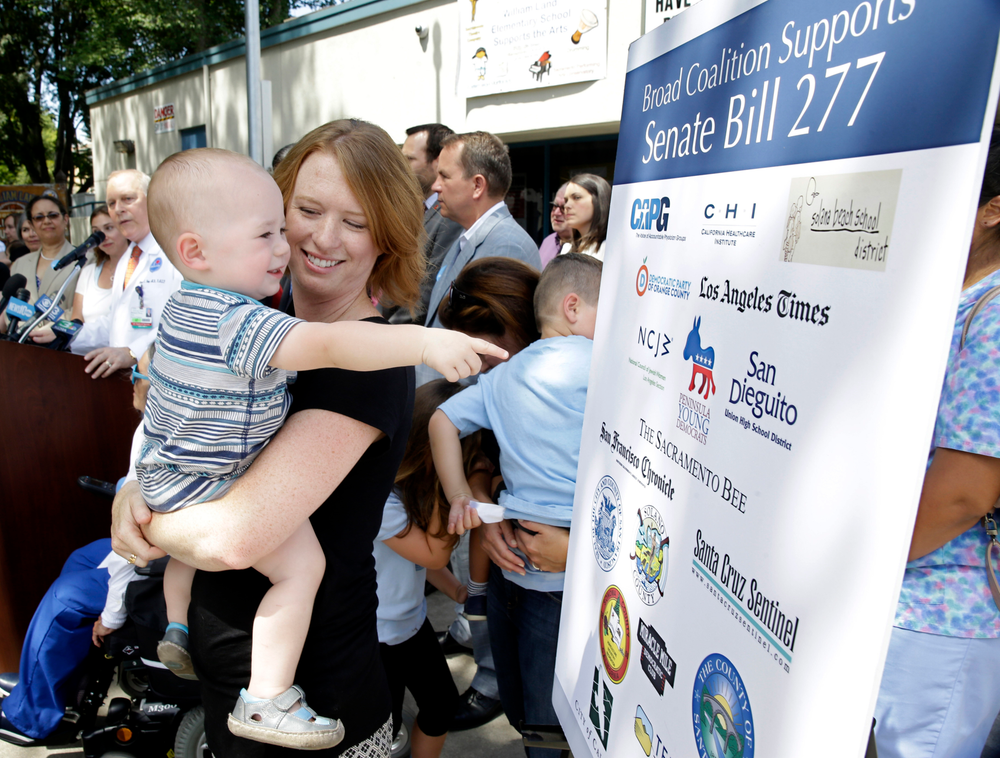 FILE - In this June 30, 2015, file photo, Jennifer Wonnacott holds her son, Gavin, as he points to a sign showing supporters of a measure requiring nearly all California school children to be vaccinated, at a news conference after the State Bill 277 was signed by Gov. Jerry Brown in Sacramento, Calif. State health officials say the number of measles cases in 2019 is up in California with cases stretching across 11 counties and affecting patients from 5 months to 55 years of age. Dr. Karen Smith, director of the California Department of Public Health, says more than 76% of patients were not vaccinated or didn't receive the recommended two doses of vaccine. Fourteen of those infected had traveled overseas to countries including Philippines, Thailand, India and Ukraine. Measles symptoms include high fever, a cough and a rash. (AP Photo/Rich Pedroncelli, File) FILE - In this June 30, 2015, file photo, Jennifer Wonnacott holds her son, Gavin, as he points to a sign showing supporters of a measure requiring nearly all California school children to be vaccinated, at a news conference after the State Bill 277 was signed by Gov. Jerry Brown in Sacramento, Calif. State health officials say the number of measles cases in 2019 is up in California with cases stretching across 11 counties and affecting patients from 5 months to 55 years of age. Dr. Karen Smith, director of the California Department of Public Health, says more than 76% of patients were not vaccinated or didn't receive the recommended two doses of vaccine. Fourteen of those infected had traveled overseas to countries including Philippines, Thailand, India and Ukraine. Measles symptoms include high fever, a cough and a rash. (AP Photo/Rich Pedroncelli, File)