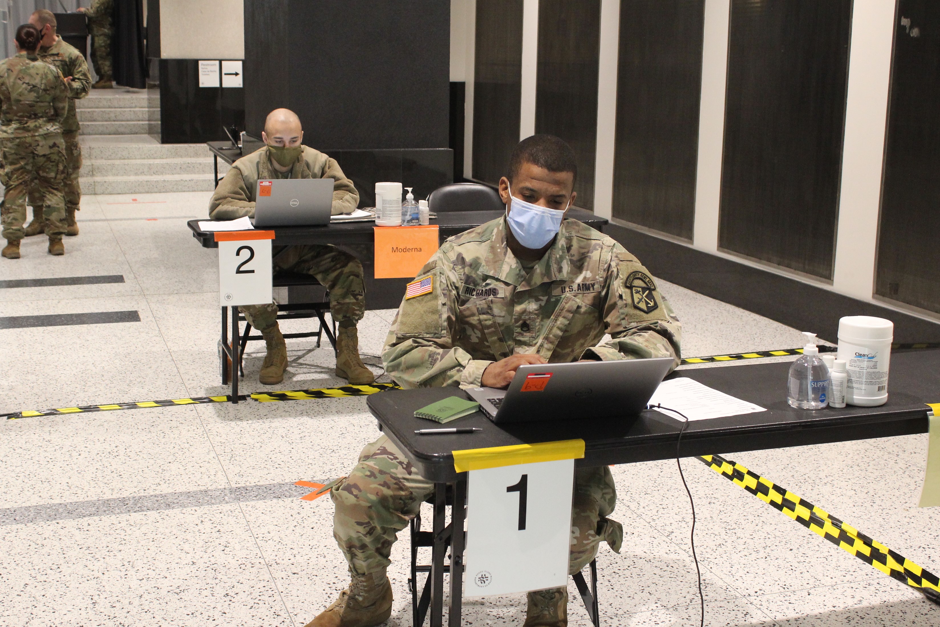 Soldiers work at the check-in tables at the new vaccination site in the Rhode Island Convention Center.