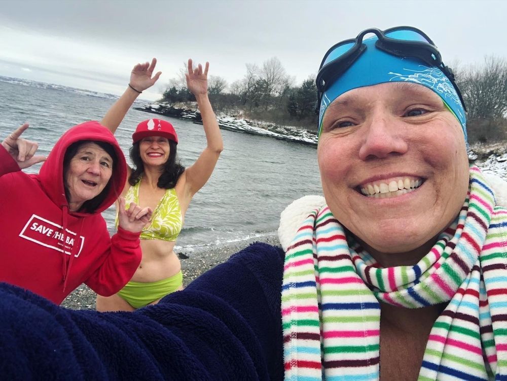 With a dusting of snow on the shore, Cathy Davis Hayes takes a selfie with Cheryl Hatch, left, and Natalie Coletta before they swim in Potter Cove in Jamestown, Rhode Island, on Dec. 24, 2021.