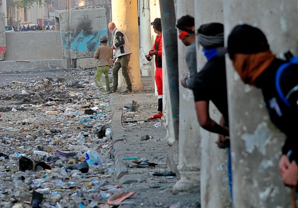 Demonstrators take cover during clashes between security forces and anti-government protesters in the historic Rasheed Street, Baghdad, Iraq, Sunday, Nov. 24, 2019. Hundreds of people have died since demonstrations began Oct. 1, when thousands of Iraqis, mostly youth, took to the streets to decry corruption and poor services. The leaderless uprising seeks to overthrow the political establishment. (AP Photo/Khalid Mohammed) Demonstrators take cover during clashes between security forces and anti-government protesters in the historic Rasheed Street, Baghdad, Iraq, Sunday, Nov. 24, 2019. Hundreds of people have died since demonstrations began Oct. 1, when thousands of Iraqis, mostly youth, took to the streets to decry corruption and poor services. The leaderless uprising seeks to overthrow the political establishment. (AP Photo/Khalid Mohammed)