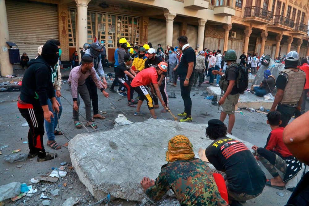 Demonstrators remove concrete walls placed by Iraqi security forces to close in the historic Rasheed Street during clashes between security forces and anti-government protesters in Baghdad, Iraq, Sunday, Nov. 24, 2019. Hundreds of people have died since demonstrations began Oct. 1, when thousands of Iraqis, mostly youth, took to the streets to decry corruption and poor services. The leaderless uprising seeks to overthrow the political establishment. (AP Photo/Khalid Mohammed) Demonstrators remove concrete walls placed by Iraqi security forces to close in the historic Rasheed Street during clashes between security forces and anti-government protesters in Baghdad, Iraq, Sunday, Nov. 24, 2019. Hundreds of people have died since demonstrations began Oct. 1, when thousands of Iraqis, mostly youth, took to the streets to decry corruption and poor services. The leaderless uprising seeks to overthrow the political establishment. (AP Photo/Khalid Mohammed)