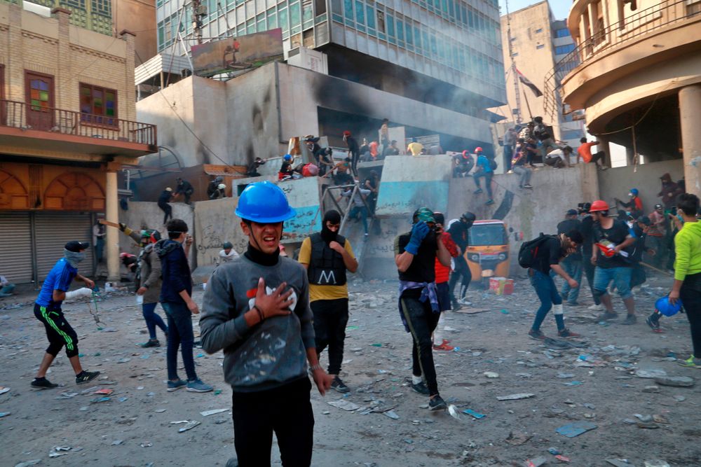 Protesters react to tear gas fired by riot police during clashes between security forces and anti-government protesters in Baghdad, Iraq, Sunday, Nov. 24, 2019. Hundreds of people have died since demonstrations began Oct. 1, when thousands of Iraqis, mostly youth, took to the streets to decry corruption and poor services. The leaderless uprising seeks to overthrow the political establishment. (AP Photo/Khalid Mohammed) Protesters react to tear gas fired by riot police during clashes between security forces and anti-government protesters in Baghdad, Iraq, Sunday, Nov. 24, 2019. Hundreds of people have died since demonstrations began Oct. 1, when thousands of Iraqis, mostly youth, took to the streets to decry corruption and poor services. The leaderless uprising seeks to overthrow the political establishment. (AP Photo/Khalid Mohammed)