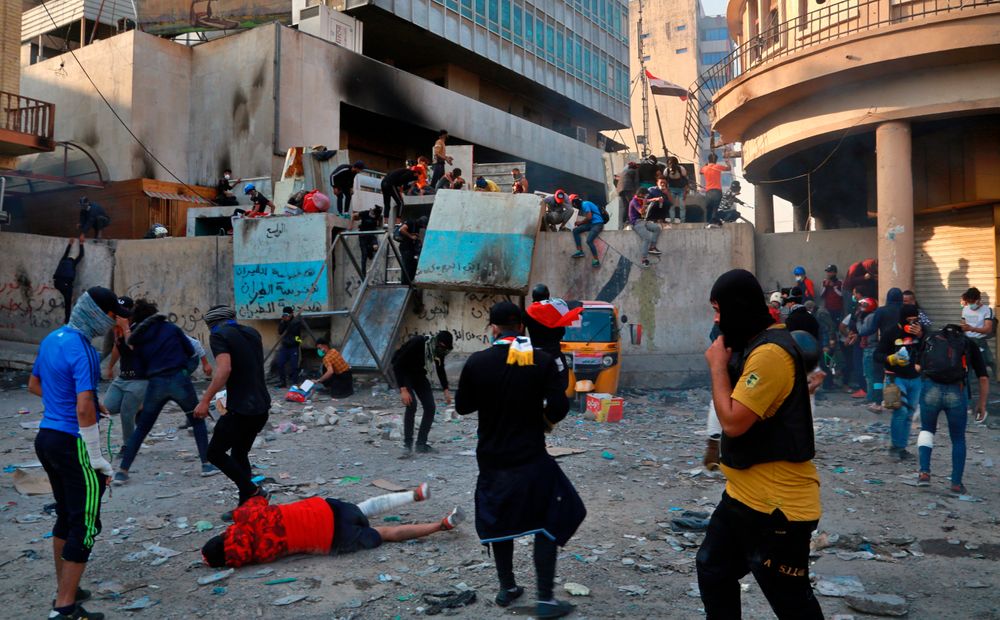 Protesters react to tear gas fired by riot police during clashes between security forces and anti-government protesters in Baghdad, Iraq, Sunday, Nov. 24, 2019. Hundreds of people have died since demonstrations began Oct. 1, when thousands of Iraqis, mostly youth, took to the streets to decry corruption and poor services. The leaderless uprising seeks to overthrow the political establishment. (AP Photo/Khalid Mohammed) Protesters react to tear gas fired by riot police during clashes between security forces and anti-government protesters in Baghdad, Iraq, Sunday, Nov. 24, 2019. Hundreds of people have died since demonstrations began Oct. 1, when thousands of Iraqis, mostly youth, took to the streets to decry corruption and poor services. The leaderless uprising seeks to overthrow the political establishment. (AP Photo/Khalid Mohammed)