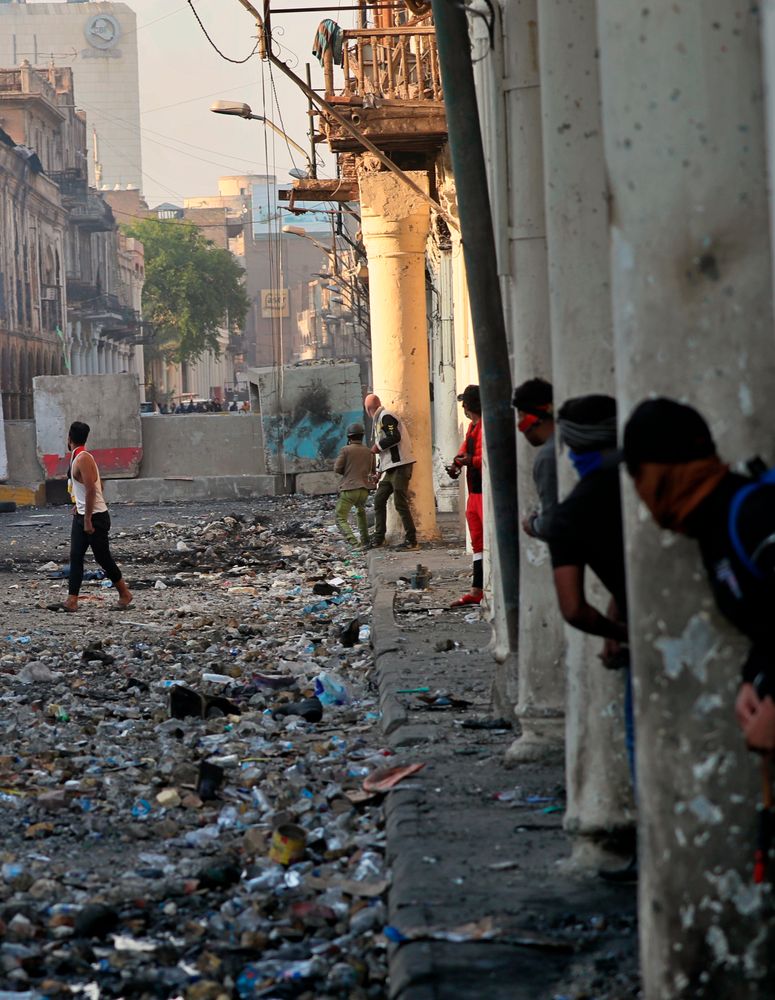 Demonstrators take cover during clashes between security forces and anti-government protesters in the historic Rasheed Street, Baghdad, Iraq, Sunday, Nov. 24, 2019. Hundreds of people have died since demonstrations began Oct. 1, when thousands of Iraqis, mostly youth, took to the streets to decry corruption and poor services. The leaderless uprising seeks to overthrow the political establishment. (AP Photo/Khalid Mohammed) Demonstrators take cover during clashes between security forces and anti-government protesters in the historic Rasheed Street, Baghdad, Iraq, Sunday, Nov. 24, 2019. Hundreds of people have died since demonstrations began Oct. 1, when thousands of Iraqis, mostly youth, took to the streets to decry corruption and poor services. The leaderless uprising seeks to overthrow the political establishment. (AP Photo/Khalid Mohammed)