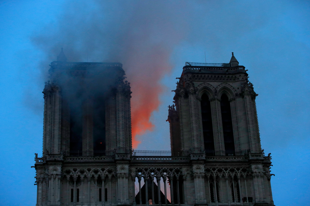 Smoke and flames fill the sky as a fire burns at the Notre Dame Cathedral during the visit by French President Emmanuel Macron in Paris, Monday, April 15, 2019. A catastrophic fire engulfed the upper reaches of Paris' soaring Notre Dame Cathedral as it was undergoing renovations Monday, threatening one of the greatest architectural treasures of the Western world as tourists and Parisians looked on aghast from the streets below.(Philippe Wojazer/Pool via AP) Smoke and flames fill the sky as a fire burns at the Notre Dame Cathedral during the visit by French President Emmanuel Macron in Paris, Monday, April 15, 2019. A catastrophic fire engulfed the upper reaches of Paris' soaring Notre Dame Cathedral as it was undergoing renovations Monday, threatening one of the greatest architectural treasures of the Western world as tourists and Parisians looked on aghast from the streets below.(Philippe Wojazer/Pool via AP)