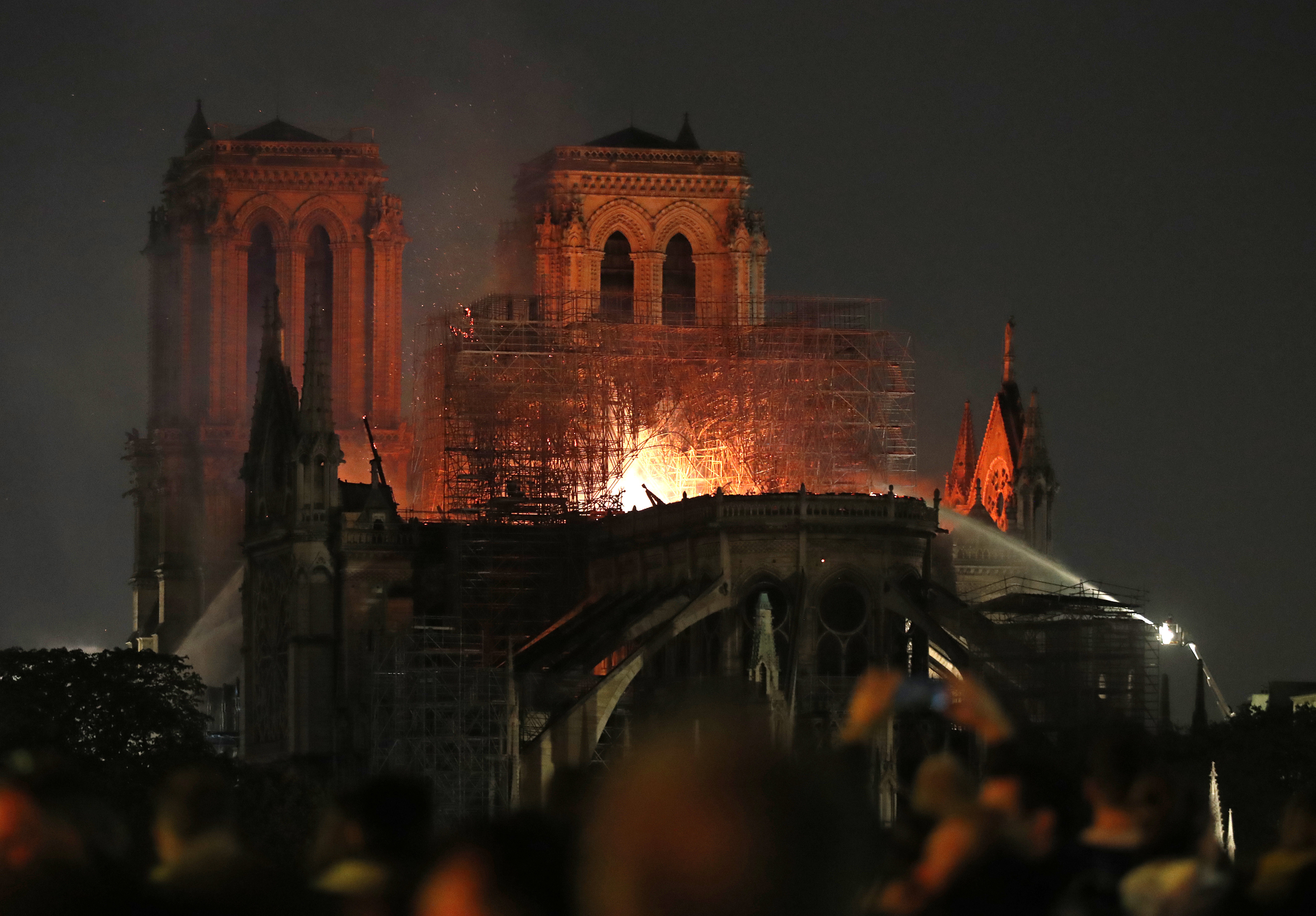Firefighters tackle the blaze as flames and smoke rise from Notre Dame cathedral as it burns in Paris, Monday, April 15, 2019. Massive plumes of yellow brown smoke is filling the air above Notre Dame Cathedral and ash is falling on tourists and others around the island that marks the center of Paris. (AP Photo/Thibault Camus) Firefighters tackle the blaze as flames and smoke rise from Notre Dame cathedral as it burns in Paris, Monday, April 15, 2019. Massive plumes of yellow brown smoke is filling the air above Notre Dame Cathedral and ash is falling on tourists and others around the island that marks the center of Paris. (AP Photo/Thibault Camus)
