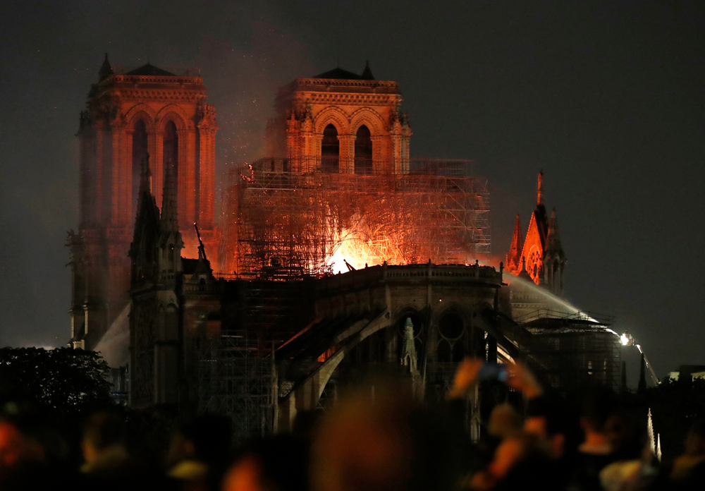 Firefighters tackle the blaze as flames and smoke rise from Notre Dame cathedral as it burns in Paris, Monday, April 15, 2019. Massive plumes of yellow brown smoke is filling the air above Notre Dame Cathedral and ash is falling on tourists and others around the island that marks the center of Paris. (AP Photo/Thibault Camus) Firefighters tackle the blaze as flames and smoke rise from Notre Dame cathedral as it burns in Paris, Monday, April 15, 2019. Massive plumes of yellow brown smoke is filling the air above Notre Dame Cathedral and ash is falling on tourists and others around the island that marks the center of Paris. (AP Photo/Thibault Camus)