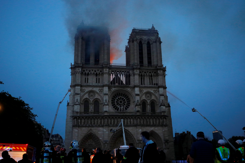 Smoke and flames fill the sky as a fire burns at the Notre Dame Cathedral during the visit by French President Emmanuel Macron in Paris, Monday, April 15, 2019. A catastrophic fire engulfed the upper reaches of Paris' soaring Notre Dame Cathedral as it was undergoing renovations Monday, threatening one of the greatest architectural treasures of the Western world as tourists and Parisians looked on aghast from the streets below.(Philippe Wojazer/Pool via AP) Smoke and flames fill the sky as a fire burns at the Notre Dame Cathedral during the visit by French President Emmanuel Macron in Paris, Monday, April 15, 2019. A catastrophic fire engulfed the upper reaches of Paris' soaring Notre Dame Cathedral as it was undergoing renovations Monday, threatening one of the greatest architectural treasures of the Western world as tourists and Parisians looked on aghast from the streets below.(Philippe Wojazer/Pool via AP)