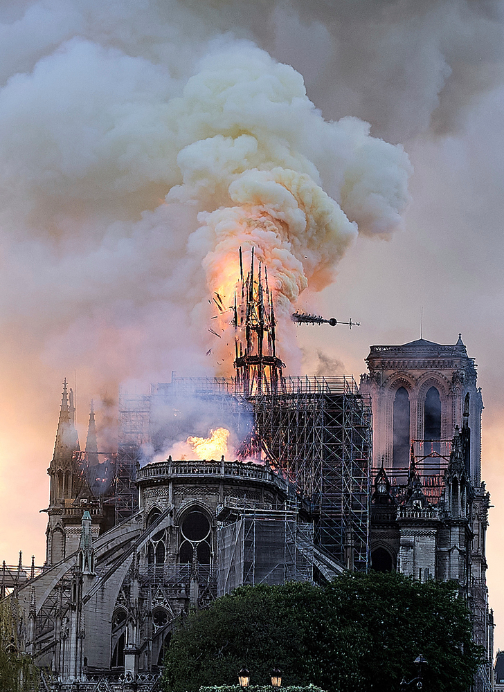 Flames and smoke rise as the spire on Notre Dame cathedral collapses in Paris, Monday, April 15, 2019. Massive plumes of yellow brown smoke is filling the air above Notre Dame Cathedral and ash is falling on tourists and others around the island that marks the center of Paris. (AP Photo/Diana Ayanna) Flames and smoke rise as the spire on Notre Dame cathedral collapses in Paris, Monday, April 15, 2019. Massive plumes of yellow brown smoke is filling the air above Notre Dame Cathedral and ash is falling on tourists and others around the island that marks the center of Paris. (AP Photo/Diana Ayanna)
