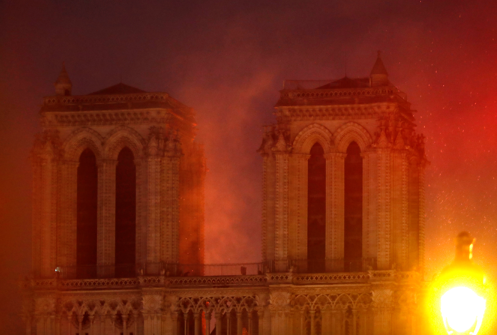 Flames illuminate the night sky as Notre Dame cathedral burns in Paris, Monday, April 15, 2019. Massive plumes of yellow brown smoke is filling the air above Notre Dame Cathedral and ash is falling on tourists and others around the island that marks the center of Paris. (AP Photo/Thibault Camus) Flames illuminate the night sky as Notre Dame cathedral burns in Paris, Monday, April 15, 2019. Massive plumes of yellow brown smoke is filling the air above Notre Dame Cathedral and ash is falling on tourists and others around the island that marks the center of Paris. (AP Photo/Thibault Camus)